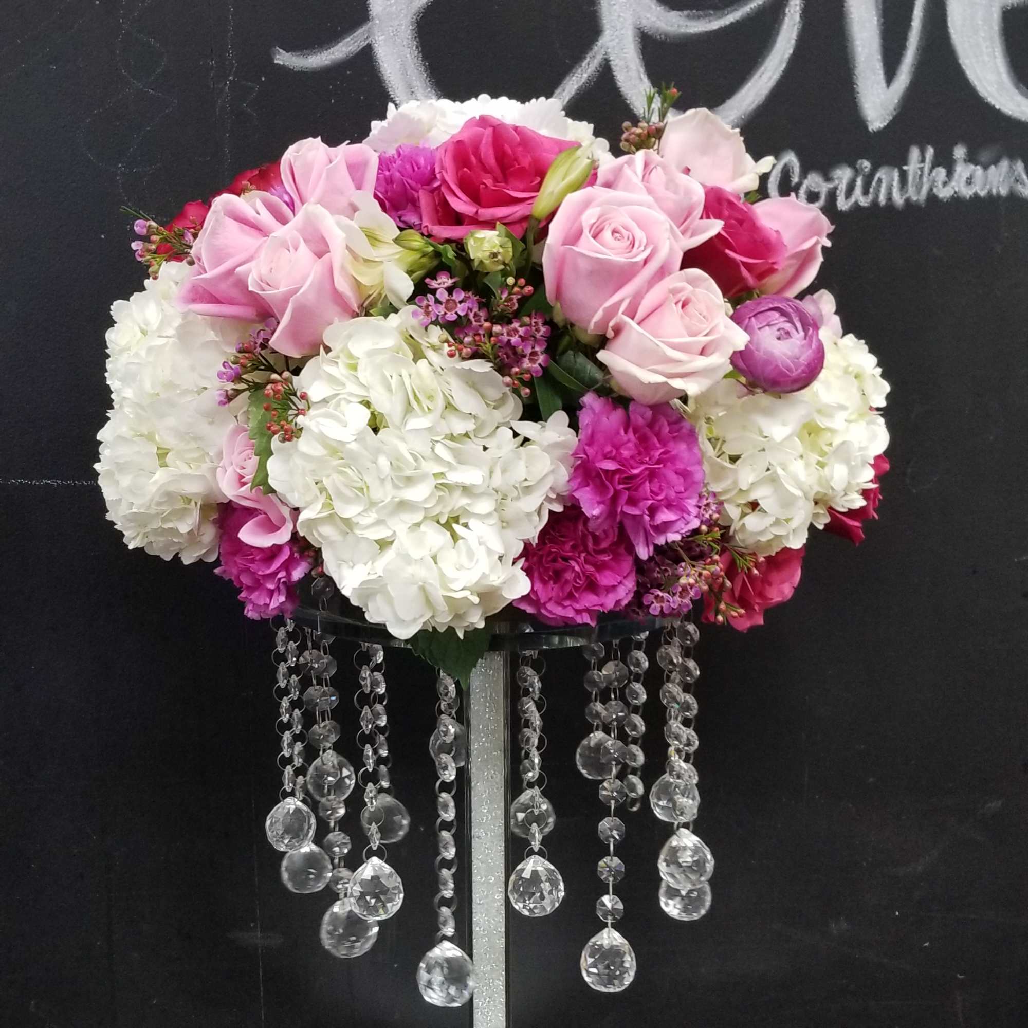 Pink and white floral arrangement on a tall stand with hanging crystal strands