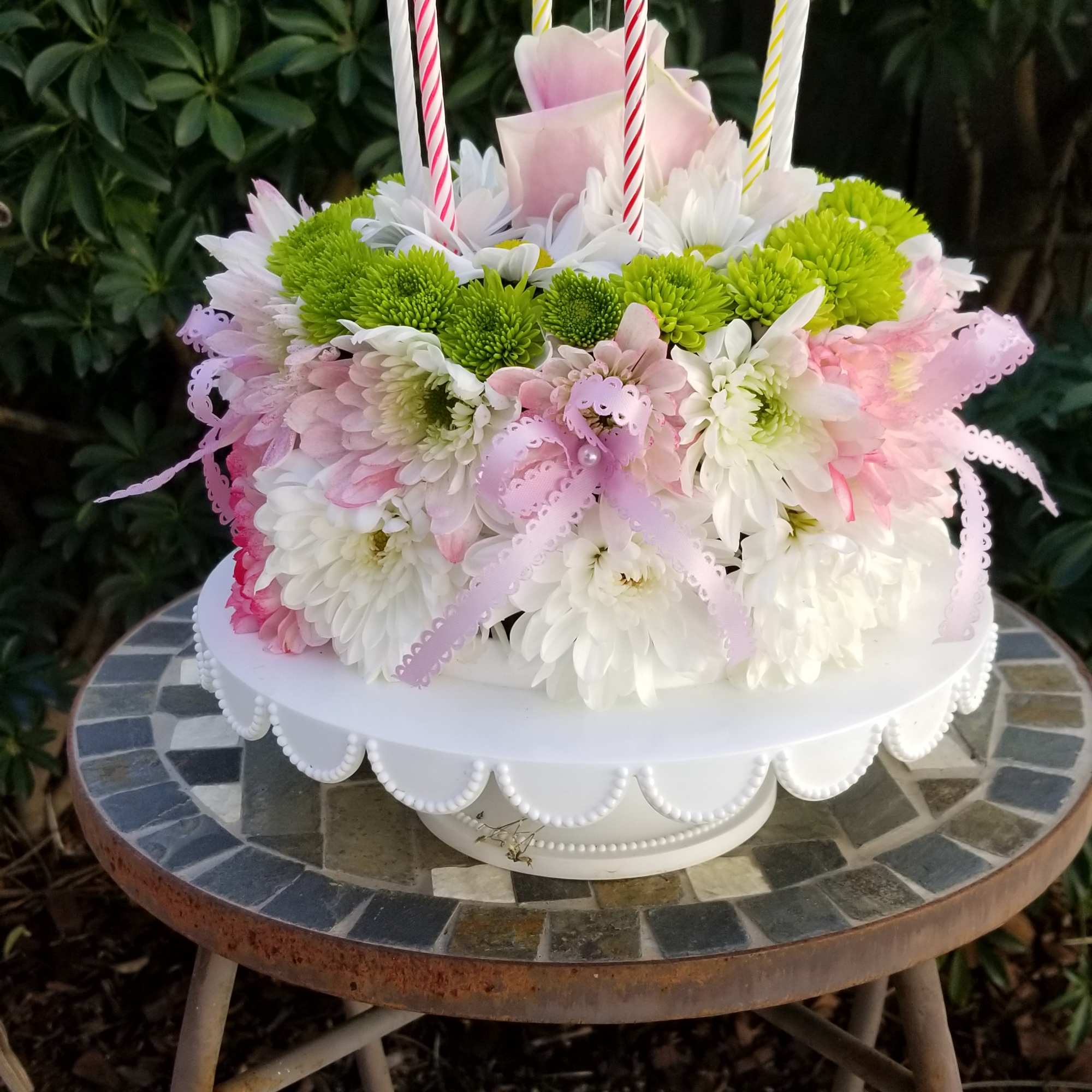 Round floral cake with candles on a white stand