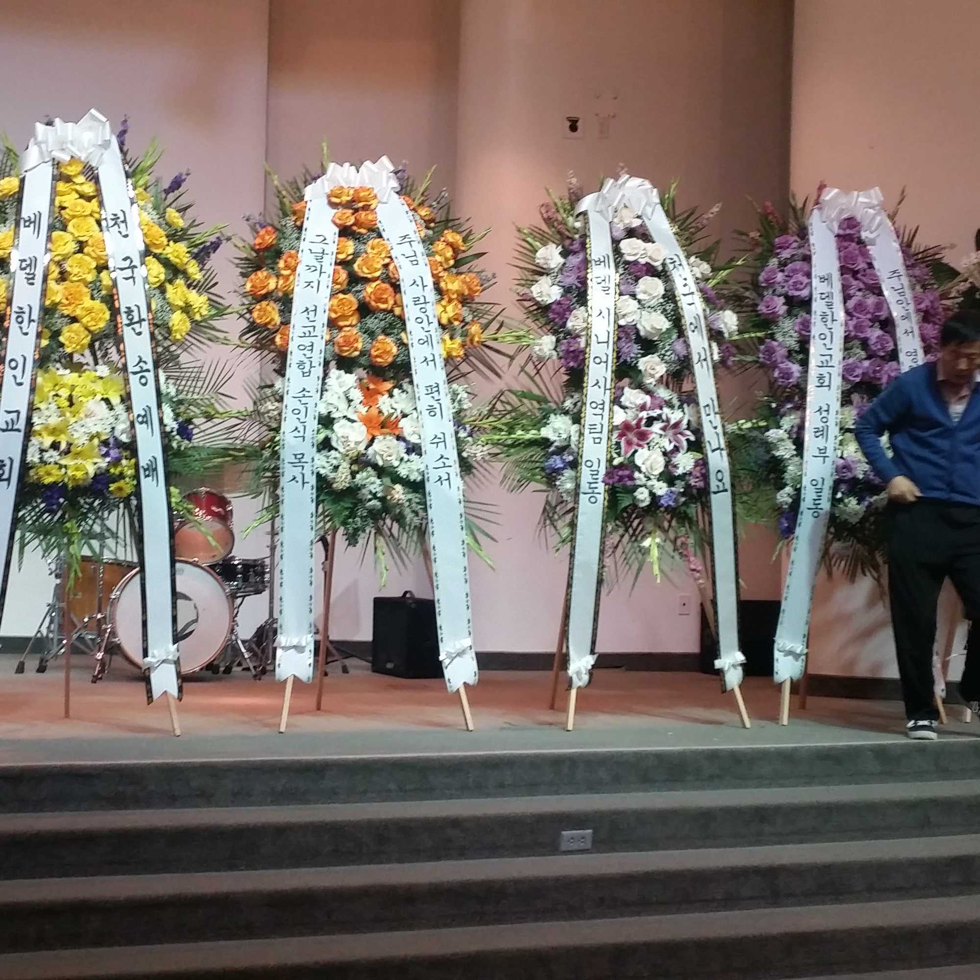 Standing funeral wreaths with ribbon banners on a stage
