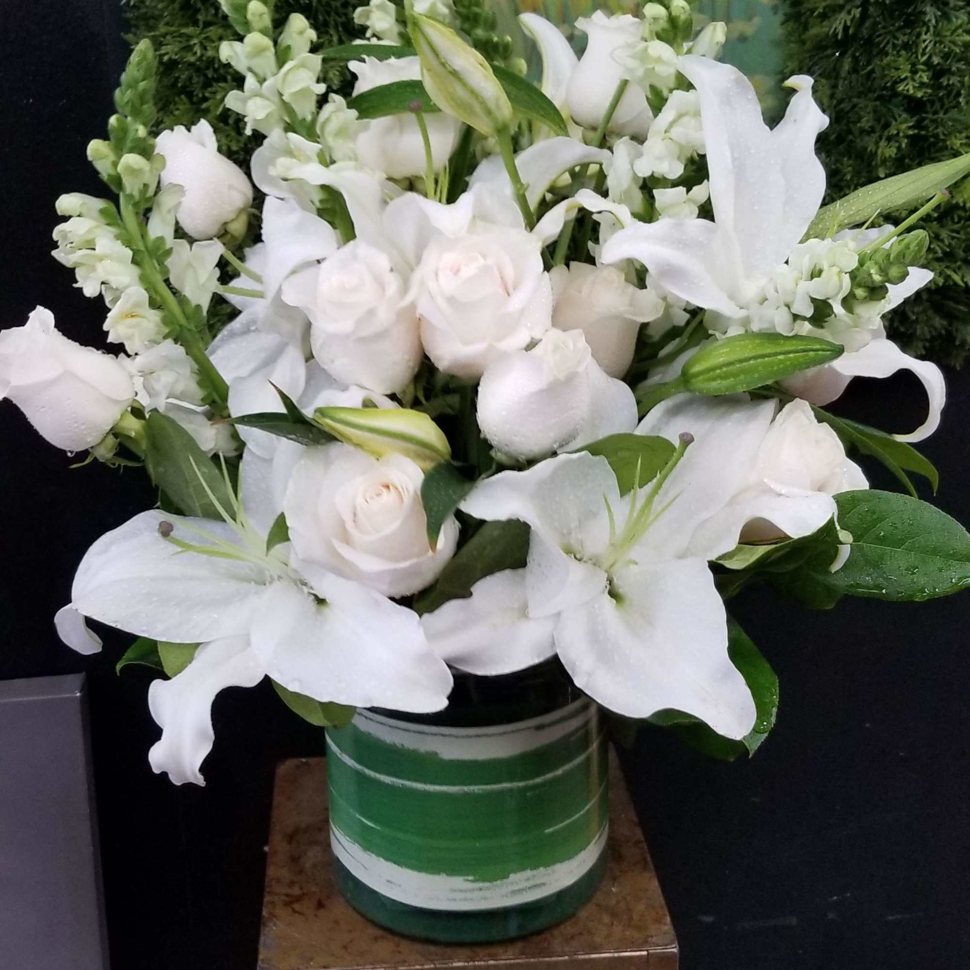 White lilies and roses arranged in a green-striped vase