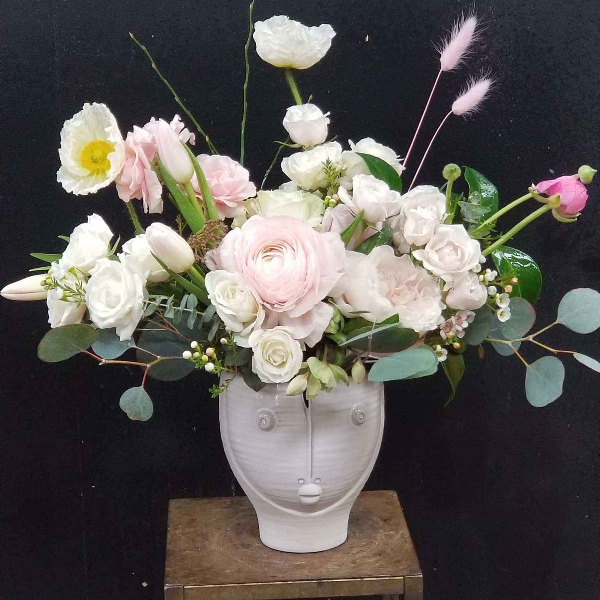 Pink and white floral arrangement in a white face-shaped vase