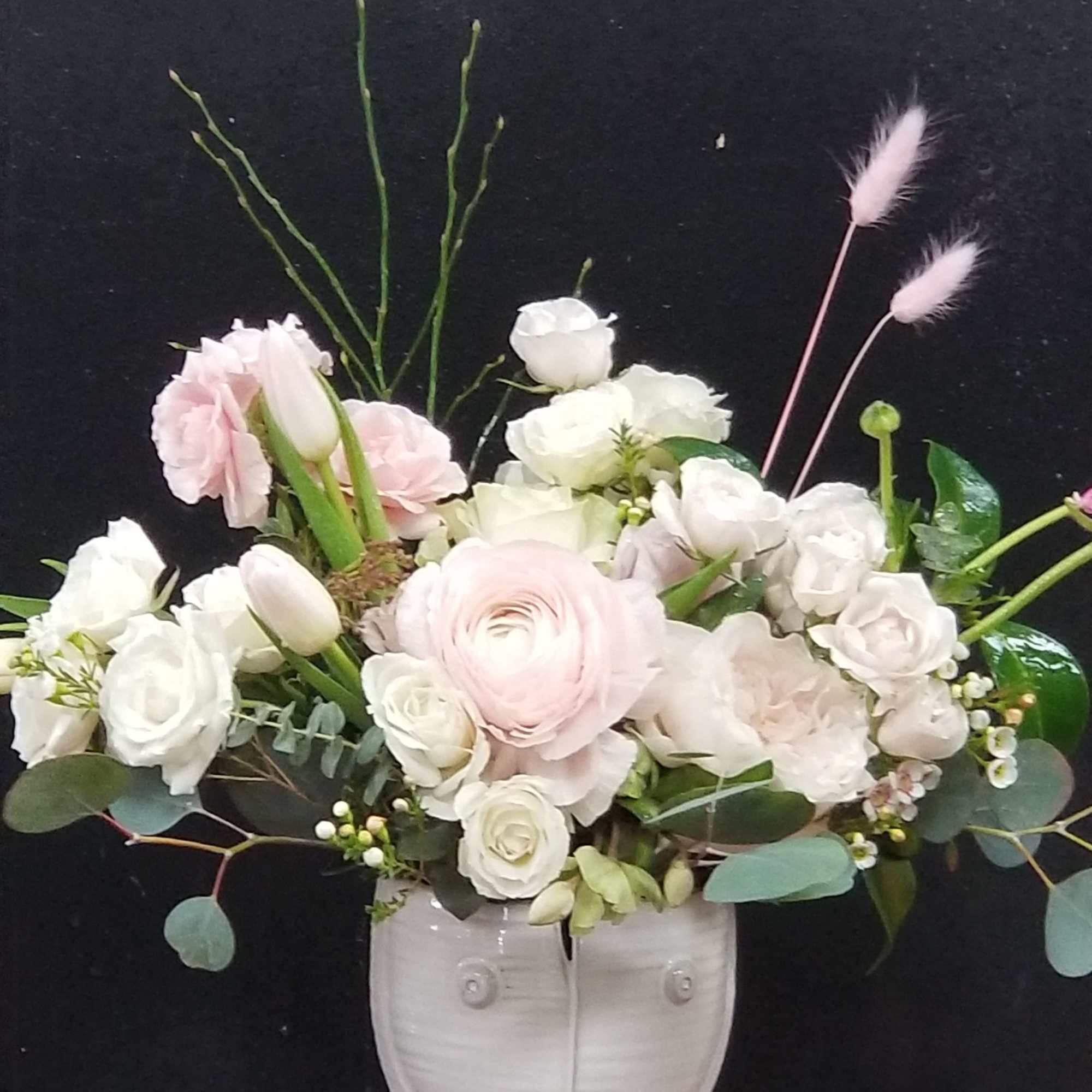 Soft pink and white floral arrangement in a white face vase