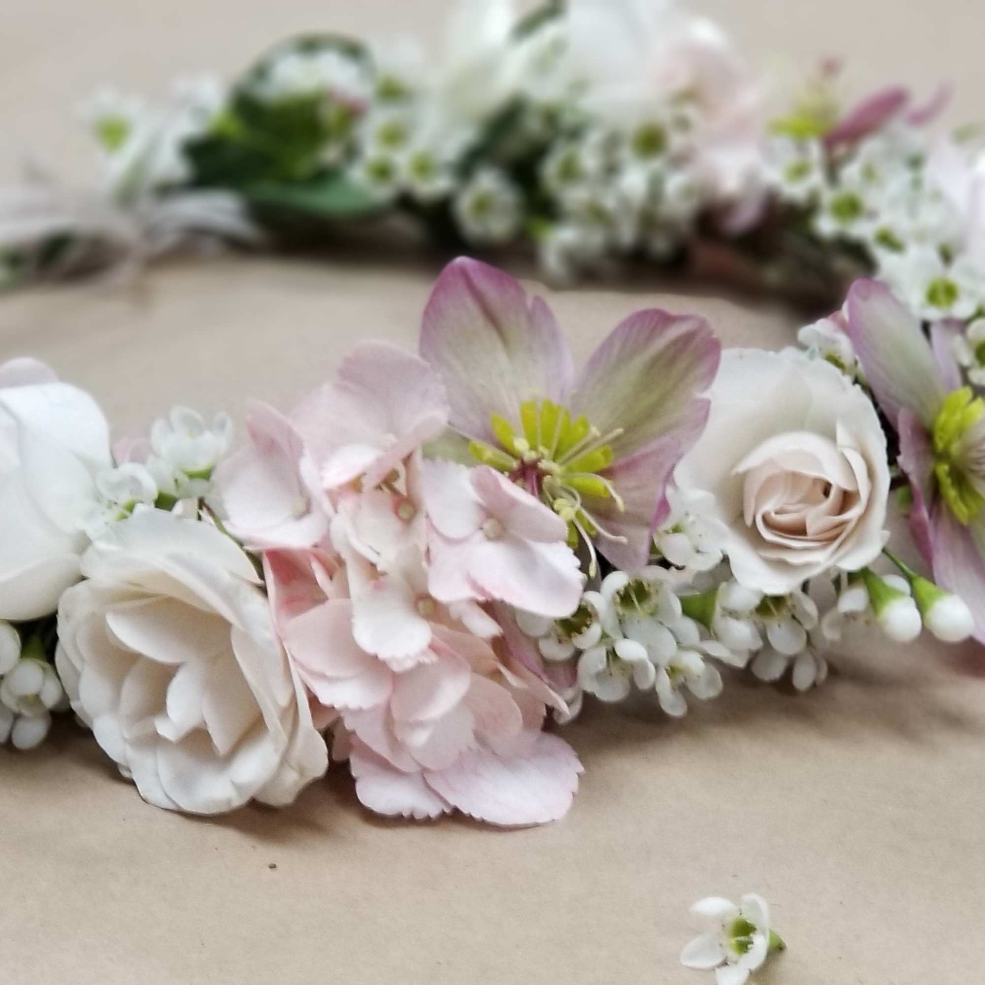 Floral crown with pink and white blossoms on a beige surface