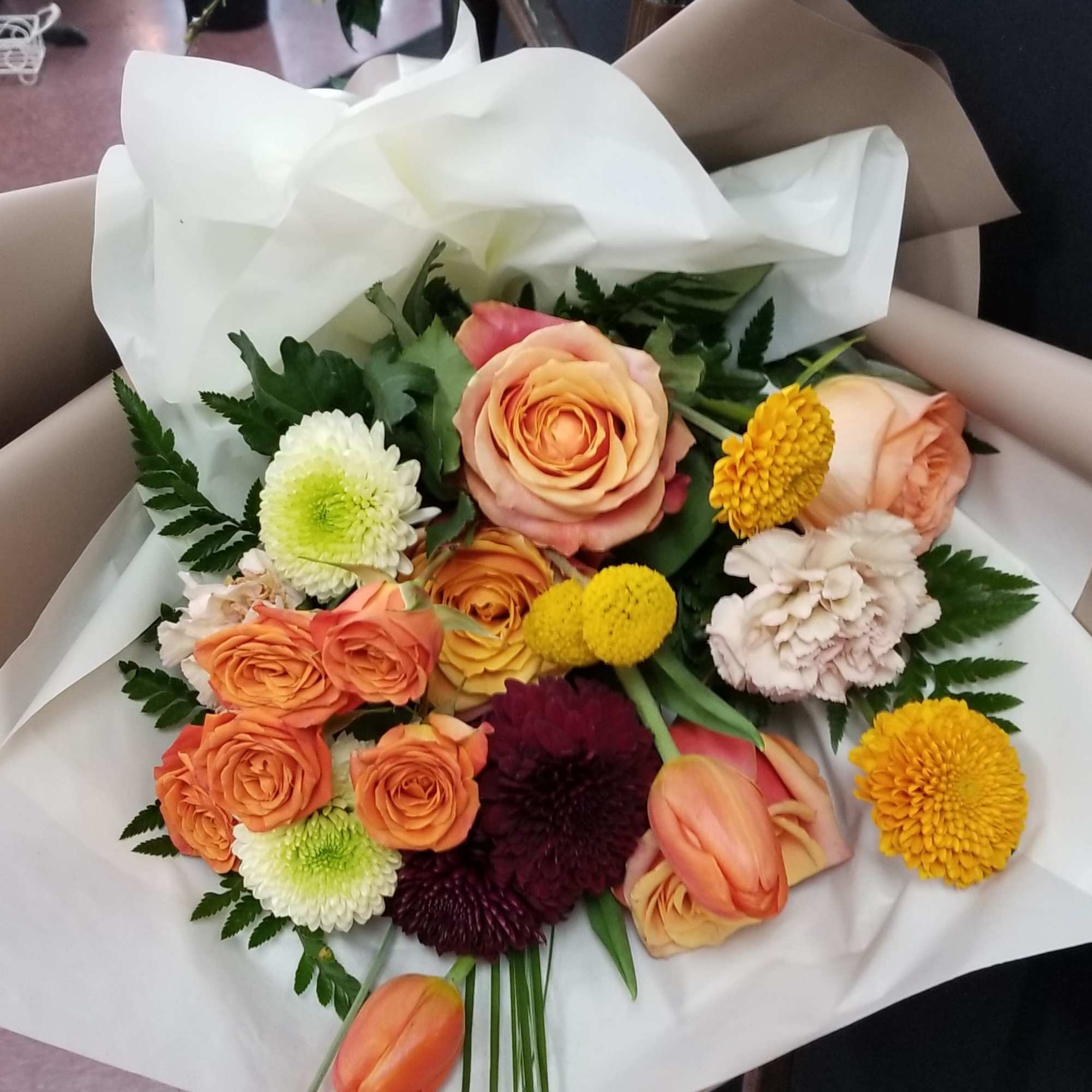 Bouquet of peach roses and mixed chrysanthemums wrapped in white paper