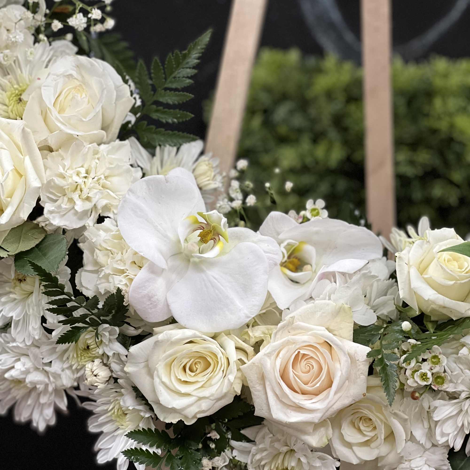 White roses and orchids arranged in a floral wreath