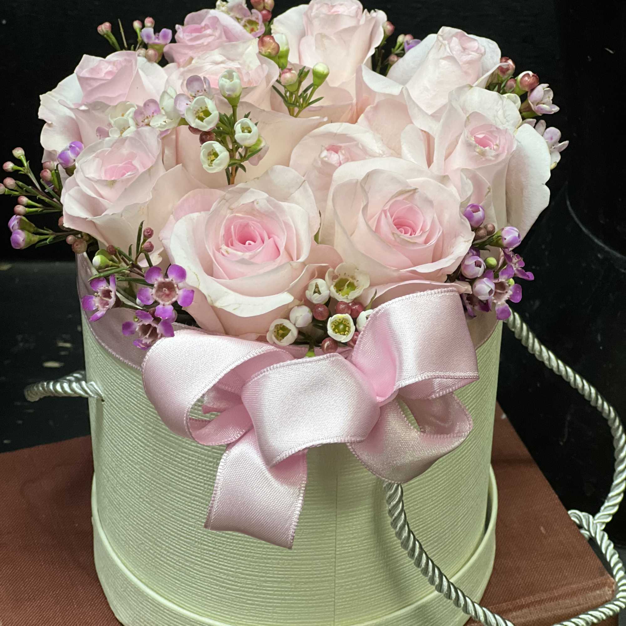 Pink roses in a round hatbox with a satin bow