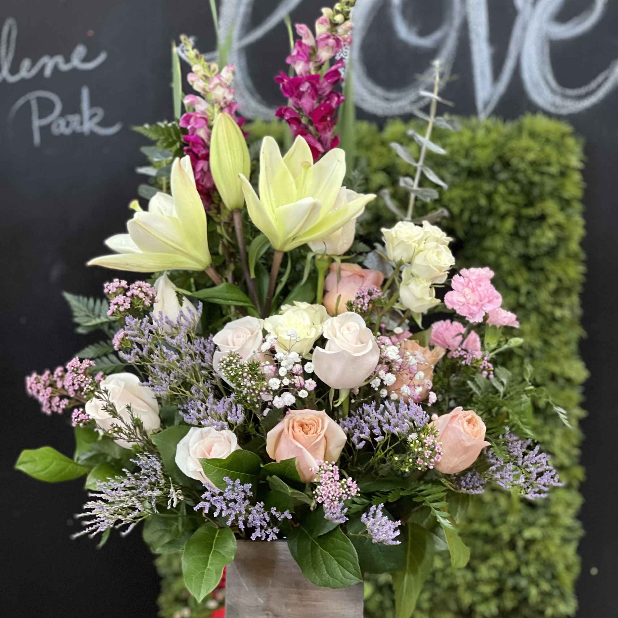 Arrangement of lilies and roses in a square vase