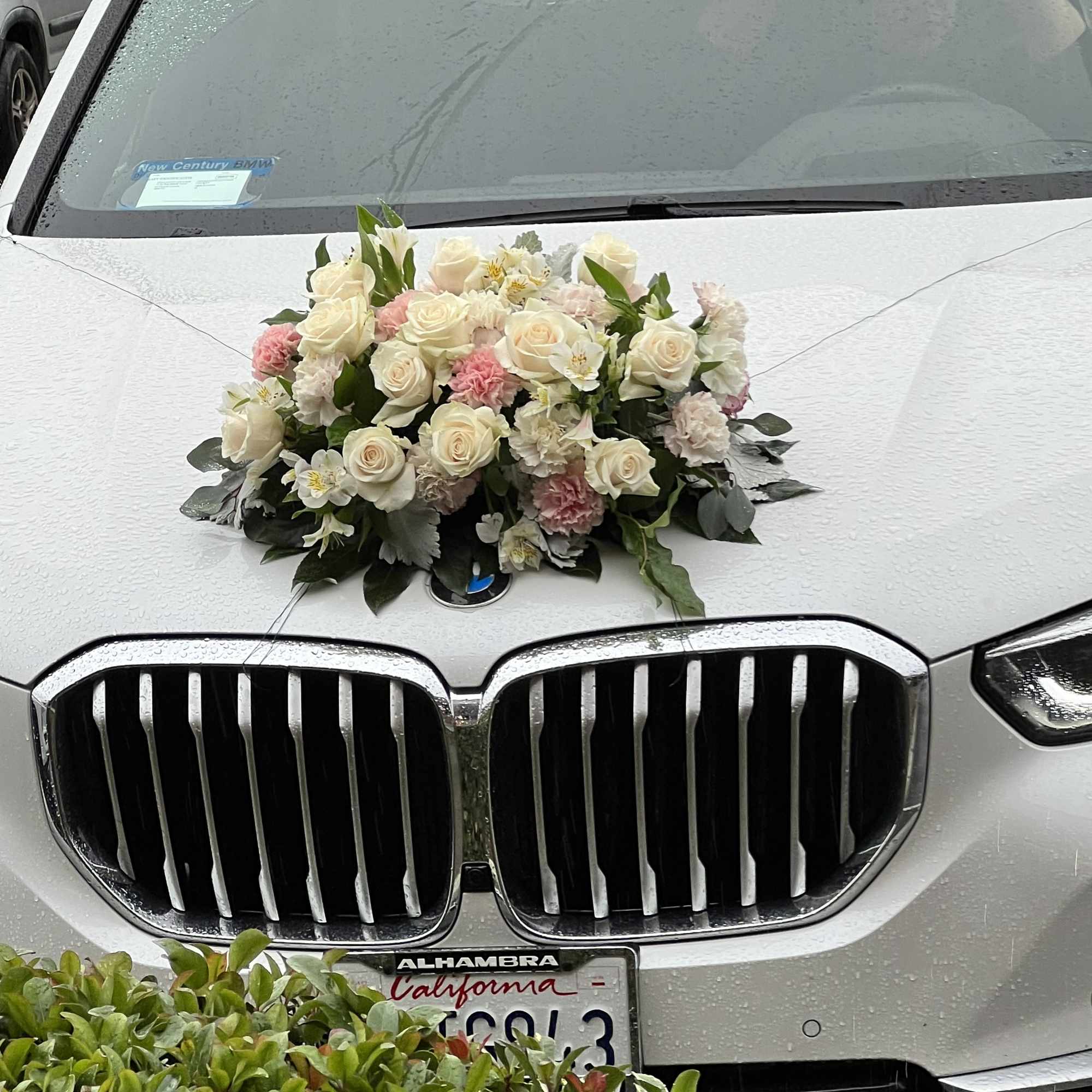 White and pink floral arrangement on the hood of a silver car