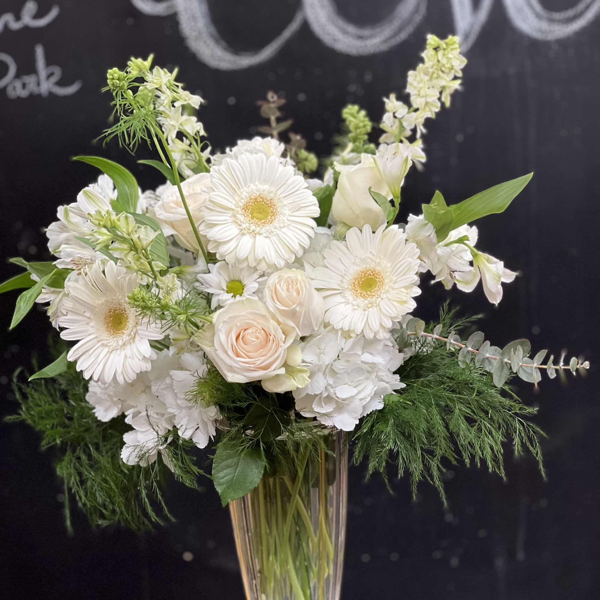 White gerbera daisies and roses in a clear glass vase