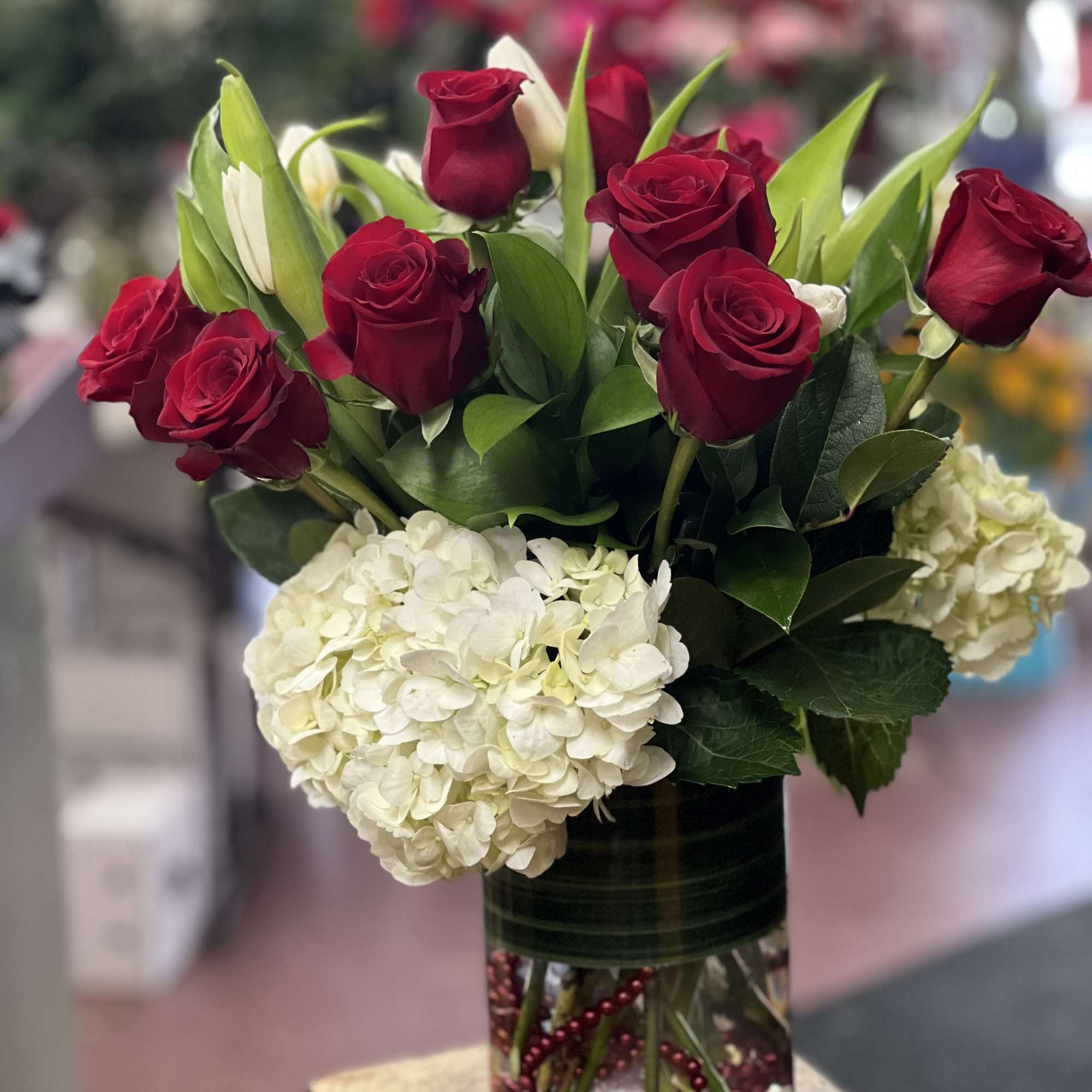 Red roses and white hydrangeas in a clear glass vase