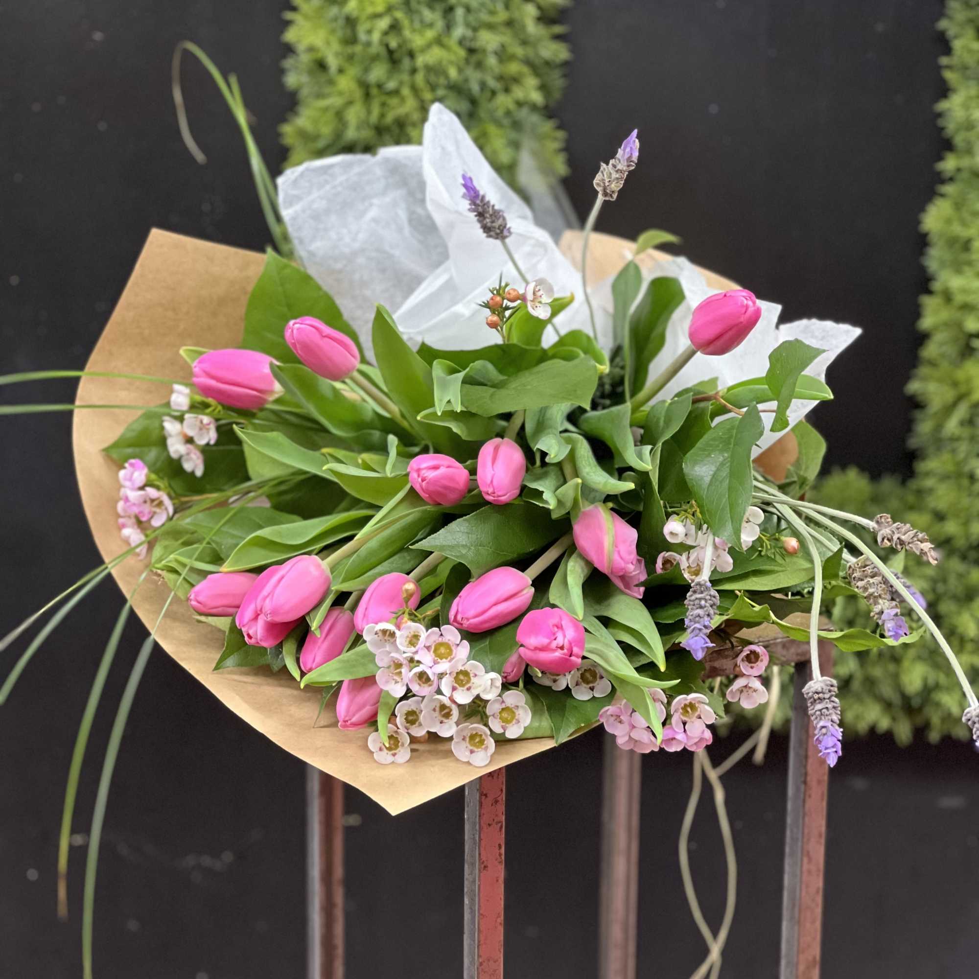 Pink tulip bouquet with small white blossoms wrapped in brown paper
