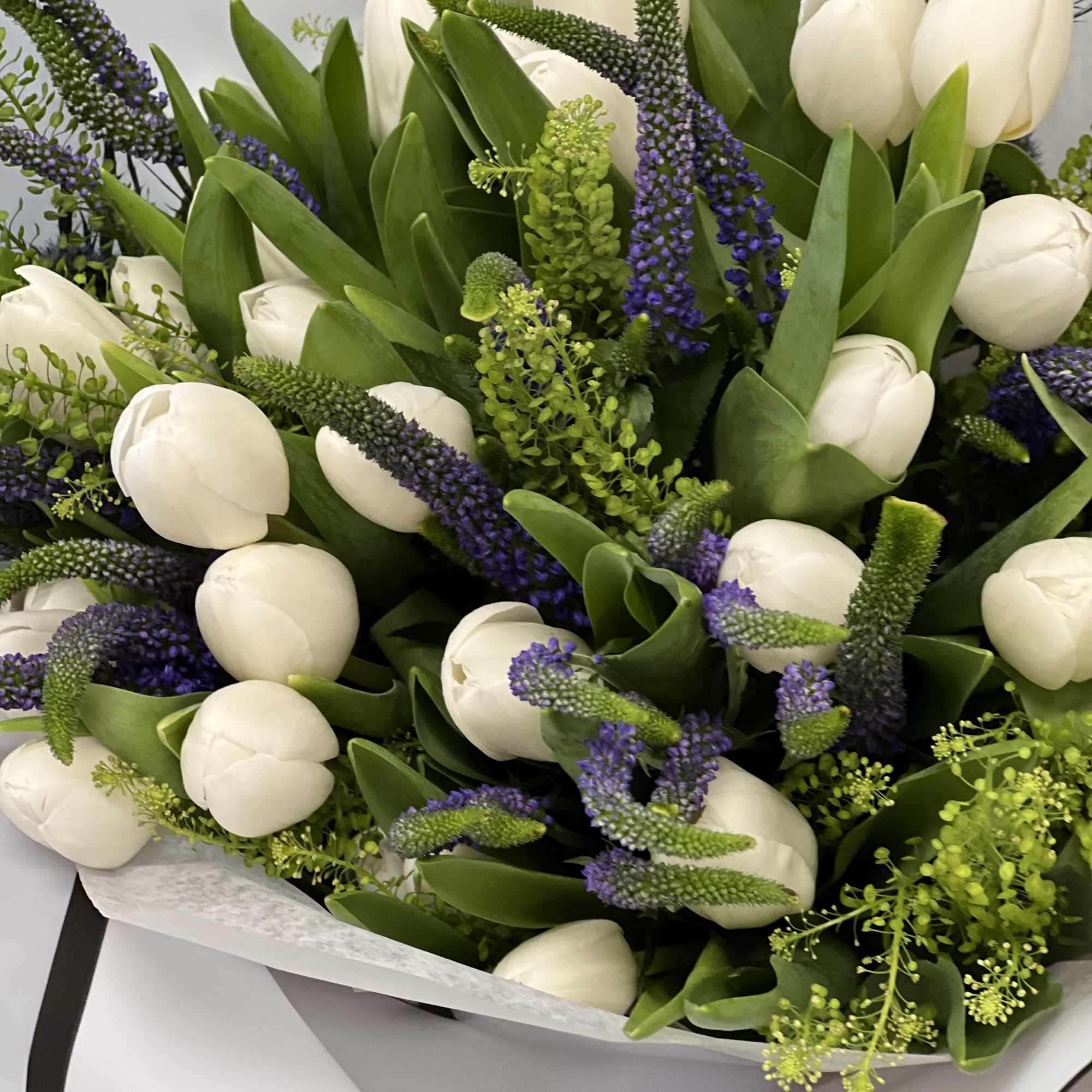 Bouquet of white tulips with purple spikes and green foliage