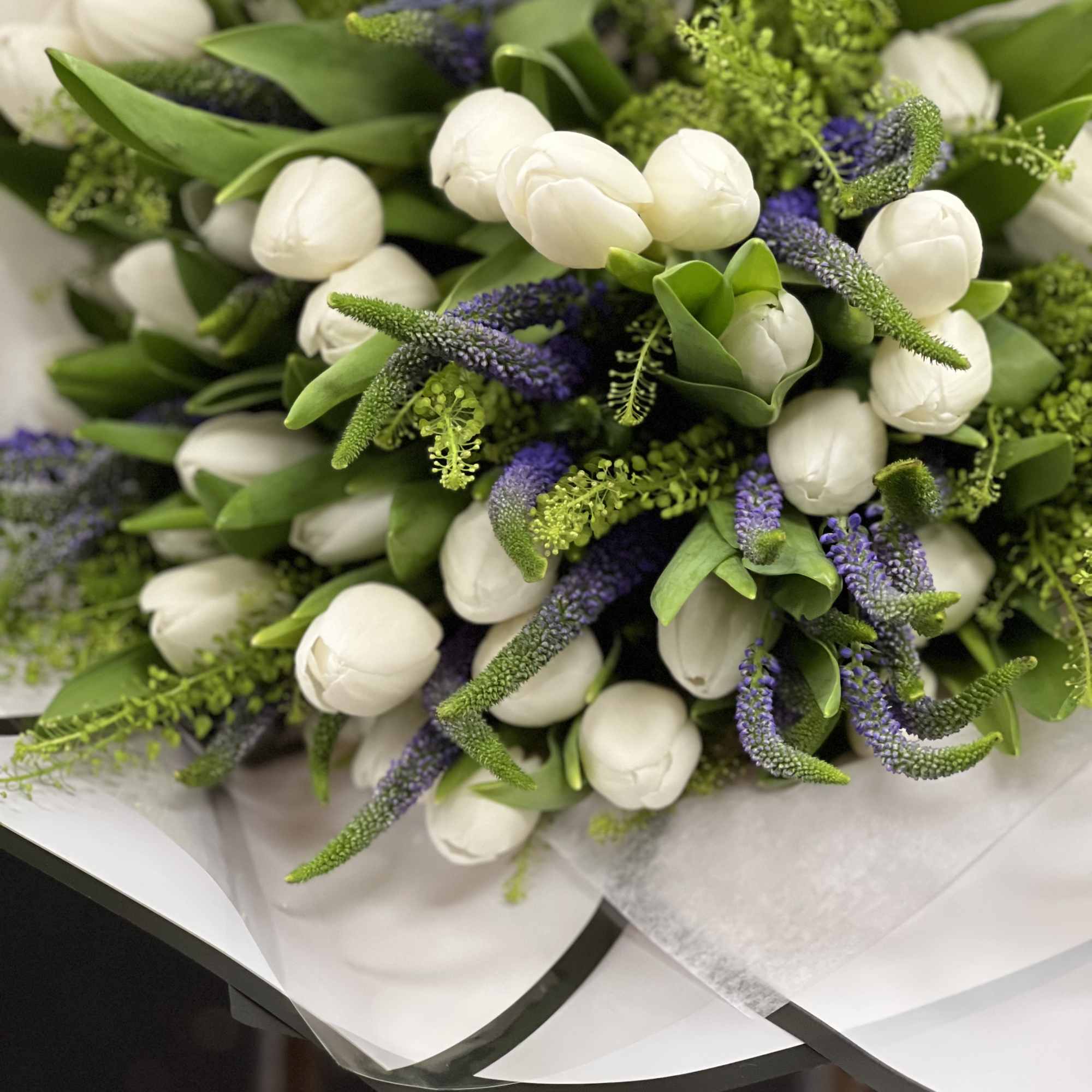 Bouquet of white tulips with purple spikes and green accents