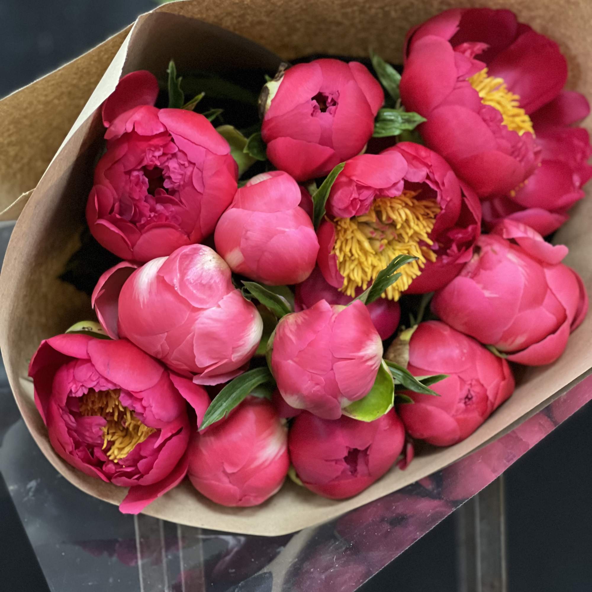 Bouquet of bright pink peonies wrapped in brown paper
