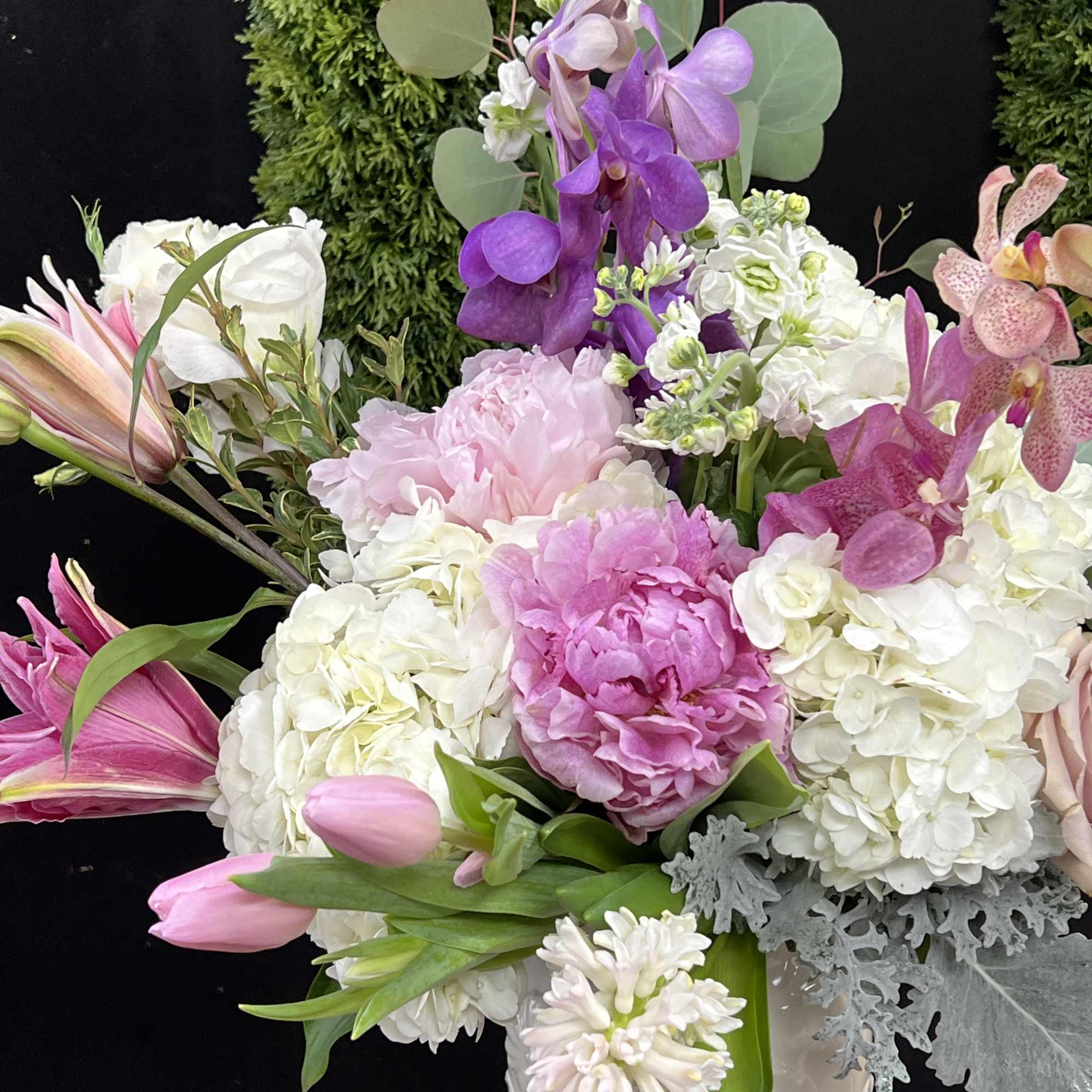Pink and white floral arrangement with orchids and tulips in a white vase