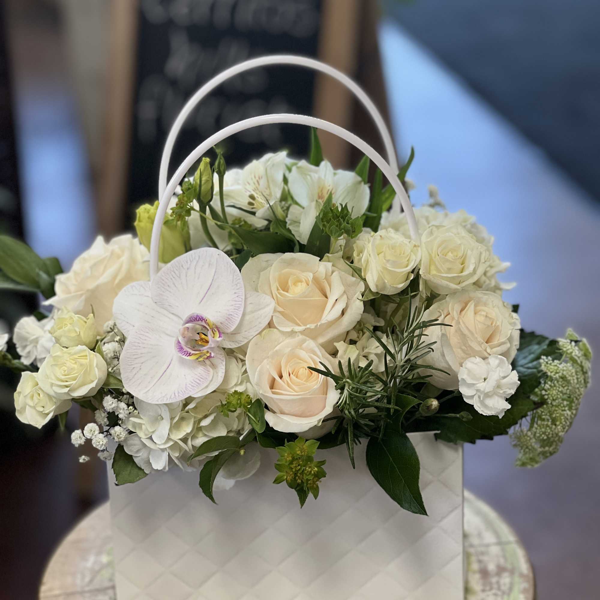 White floral arrangement in a quilted gift bag with a handle
