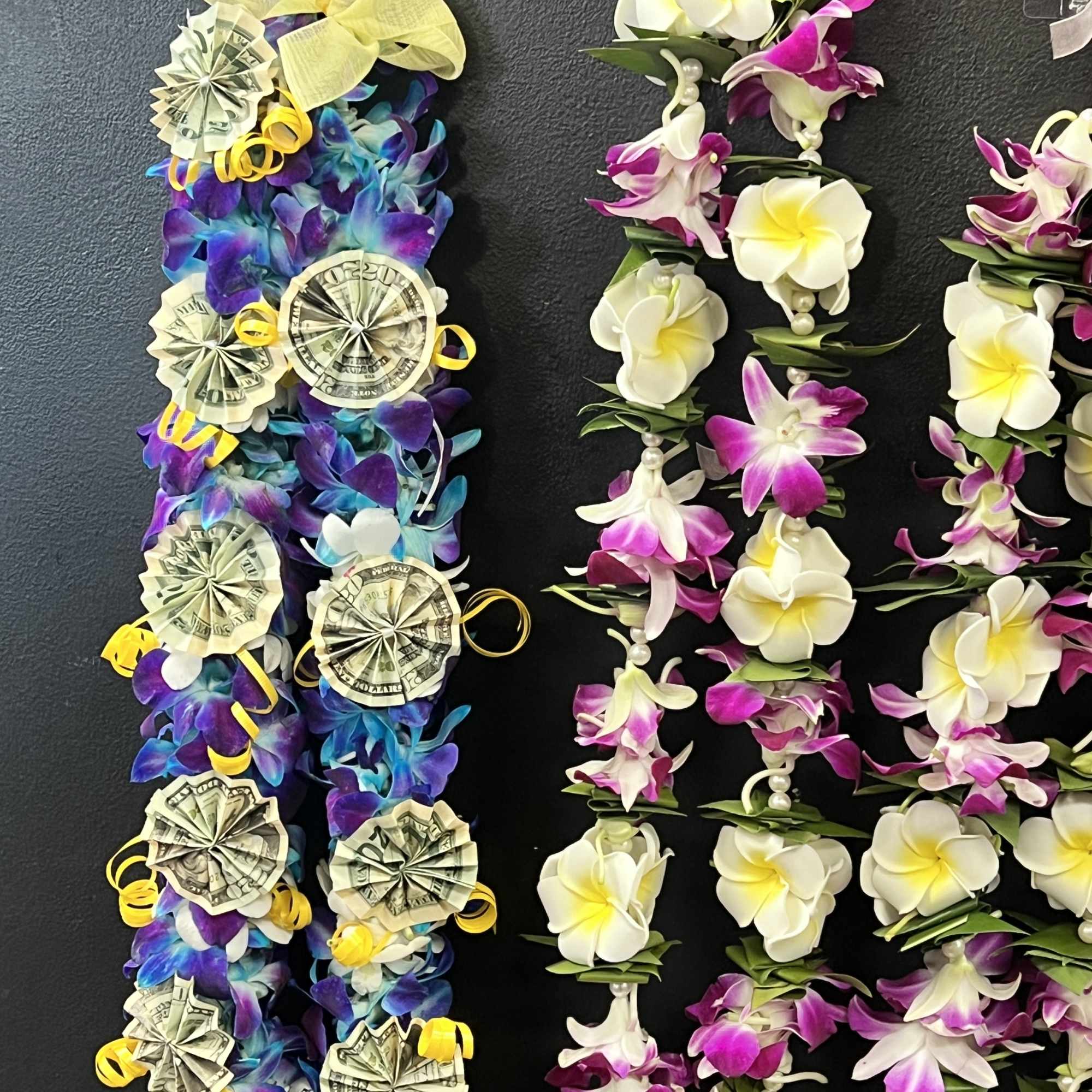 Lei-style floral garlands with white and purple flowers and money rosettes