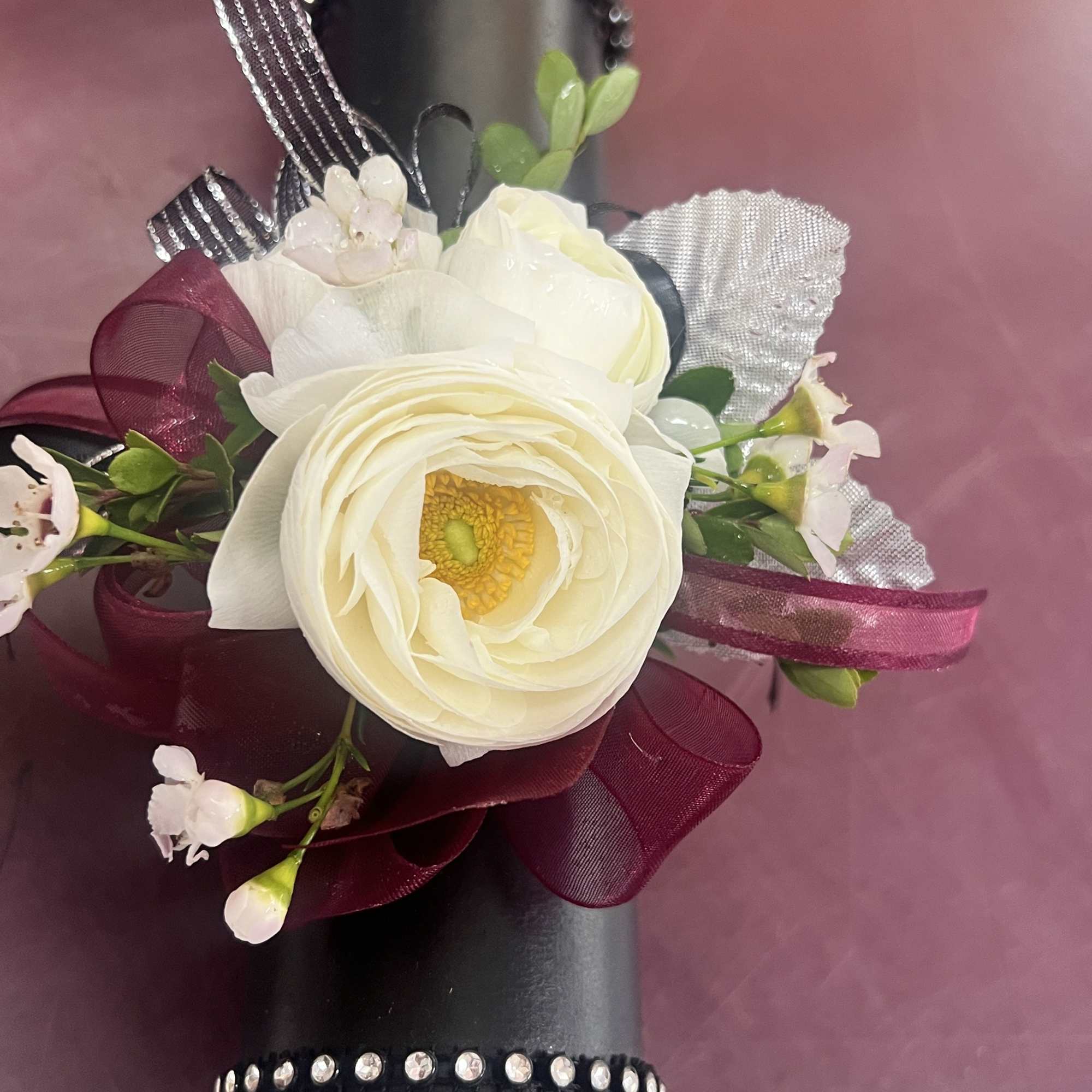 A centerpiece white phalaenopsis orchid, creamy ranunculus blooms, and glossy roses combine