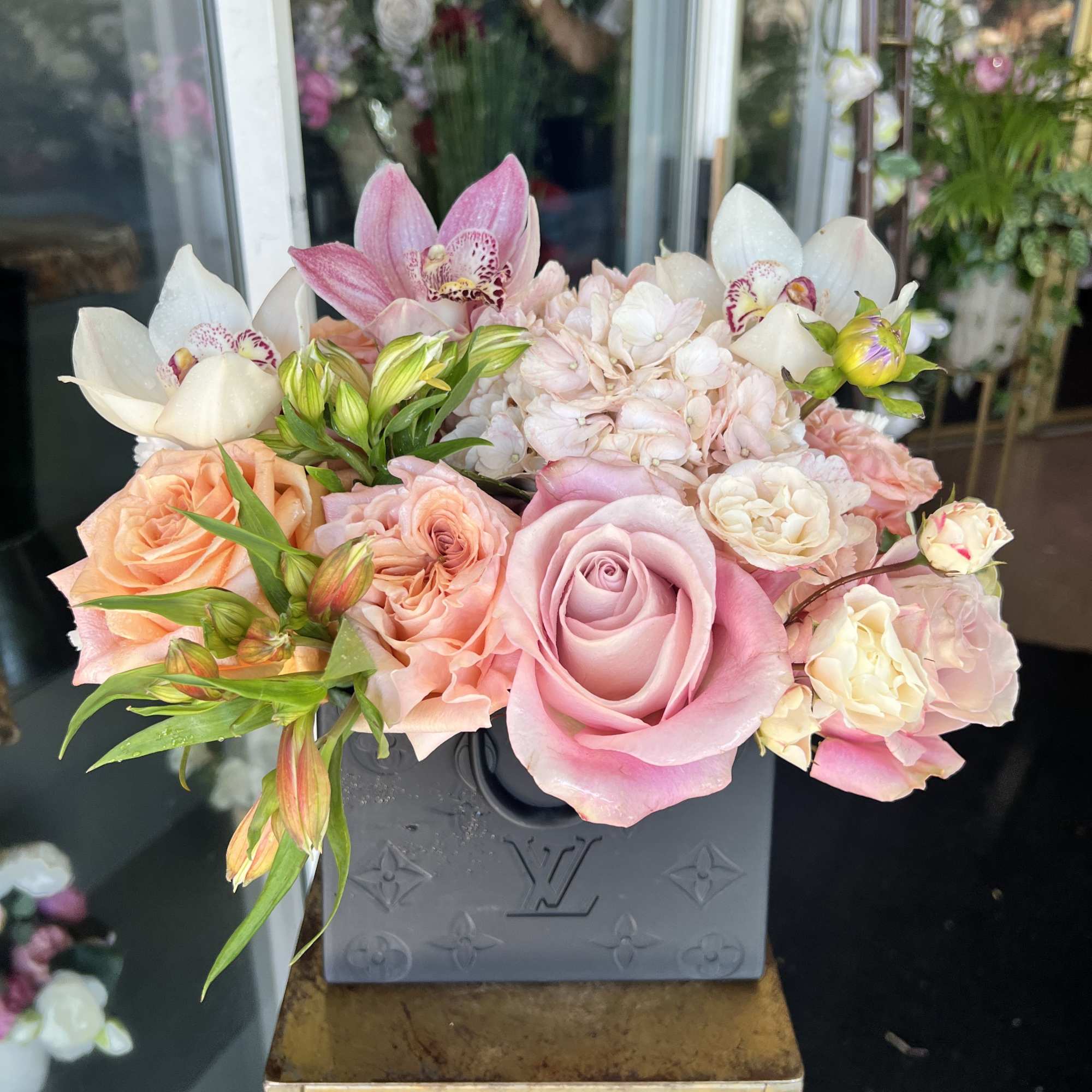 Pink and white roses with orchids in a gray box