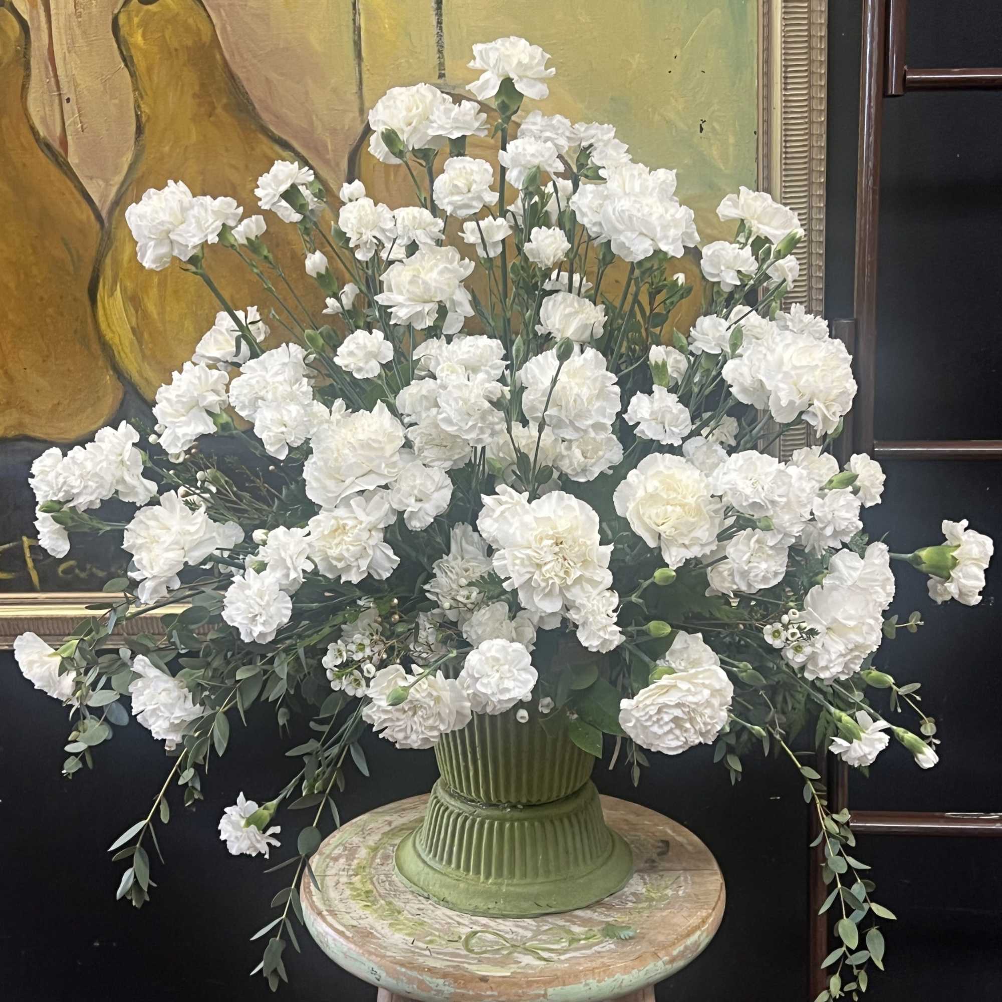 Large white carnation arrangement in a green vase