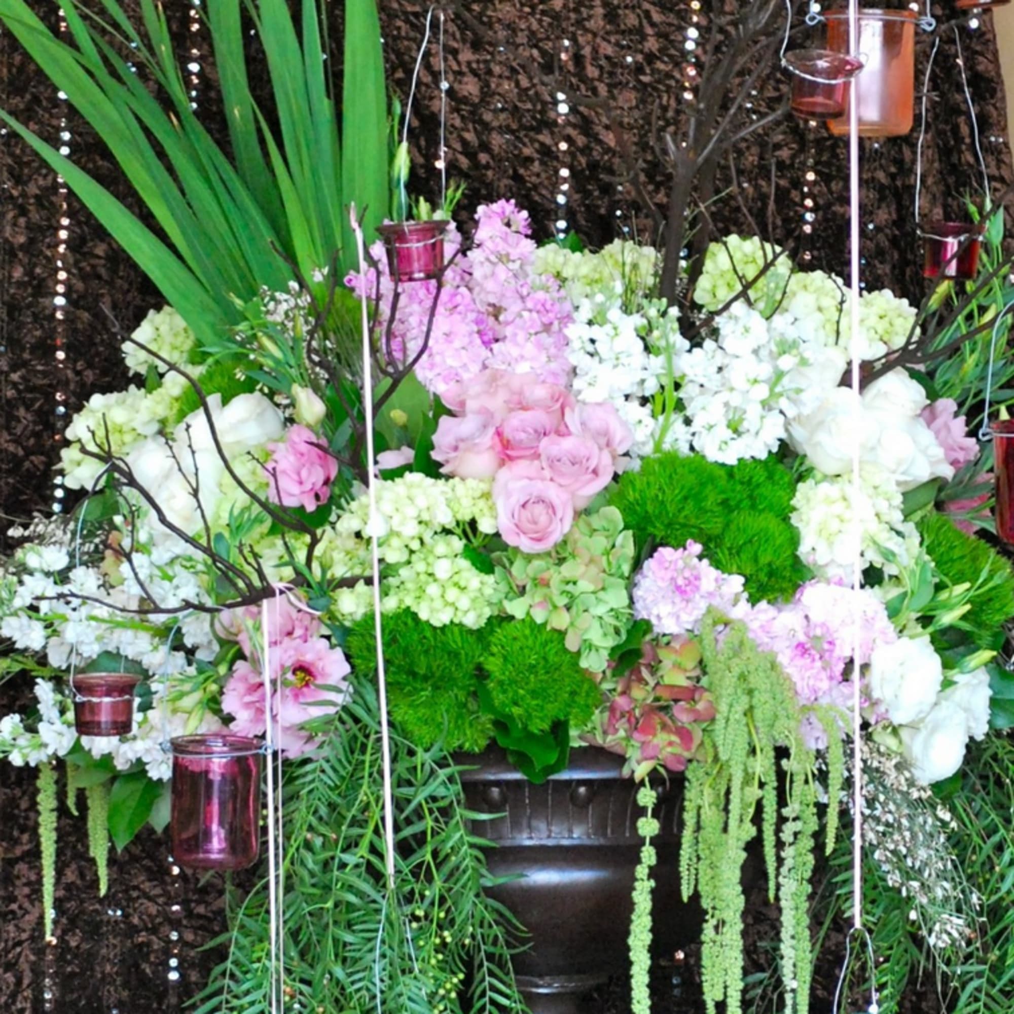 Large floral arrangement with pink and white blooms in a dark urn