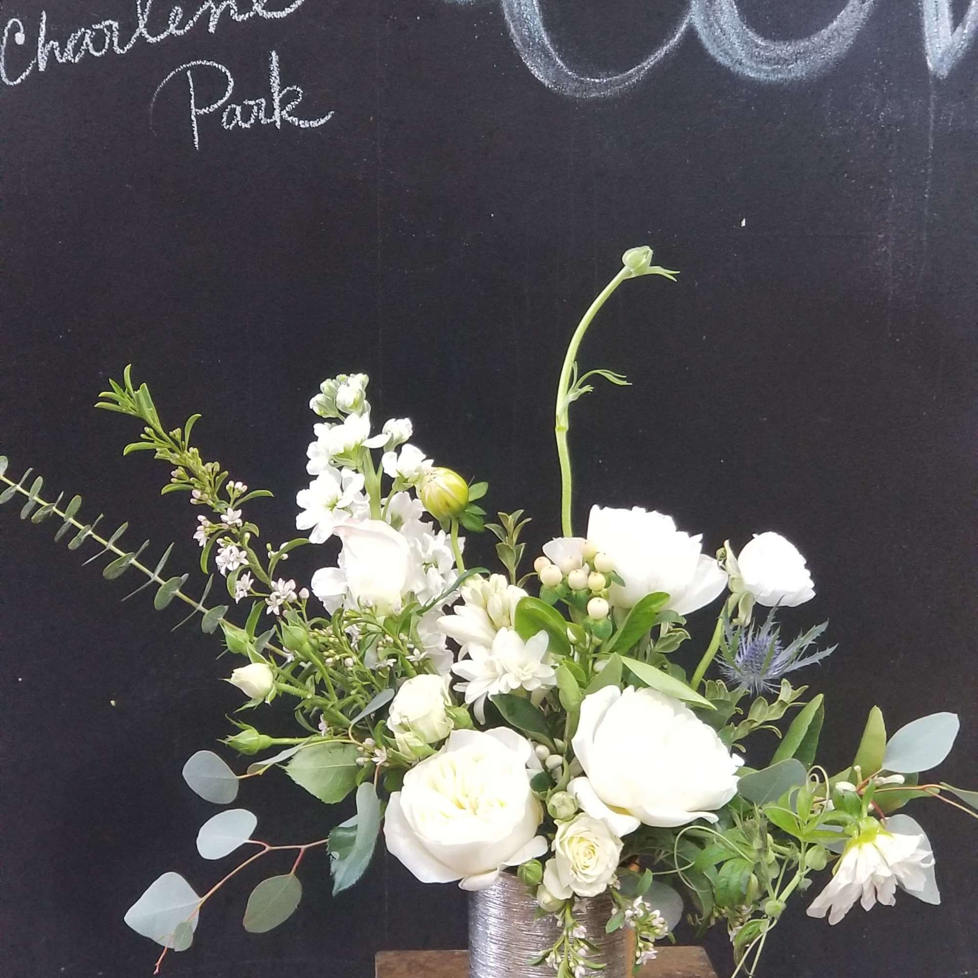 White floral arrangement in a silver vase on a small table