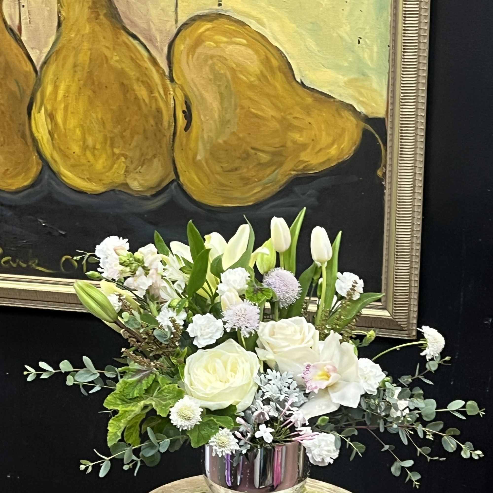 White floral arrangement in a silver vase with tulips and roses