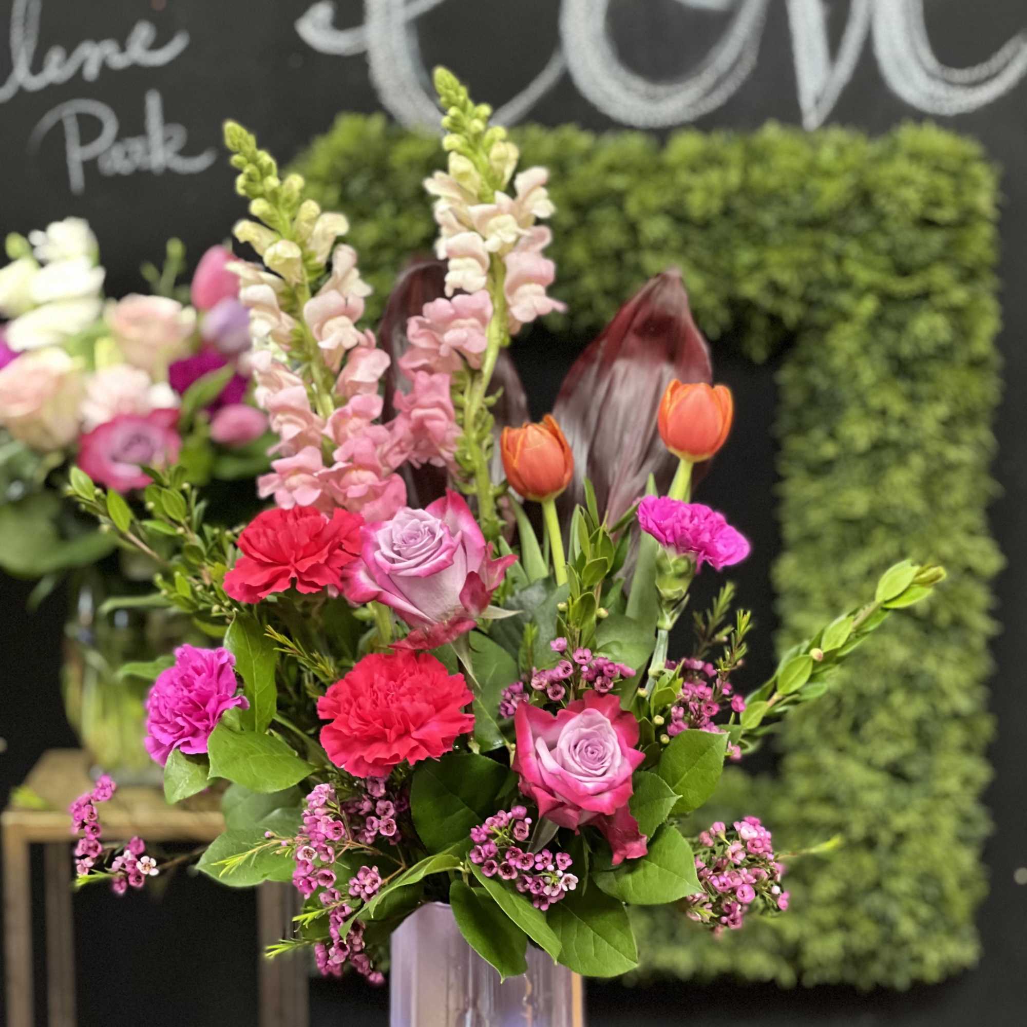 Mixed bouquet in a clear vase with pink roses, carnations, and tulips