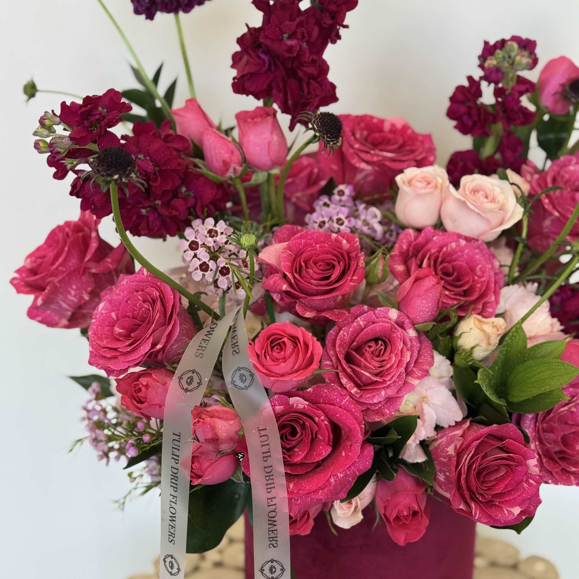 Pink and magenta rose bouquet in a tall box with ribbon
