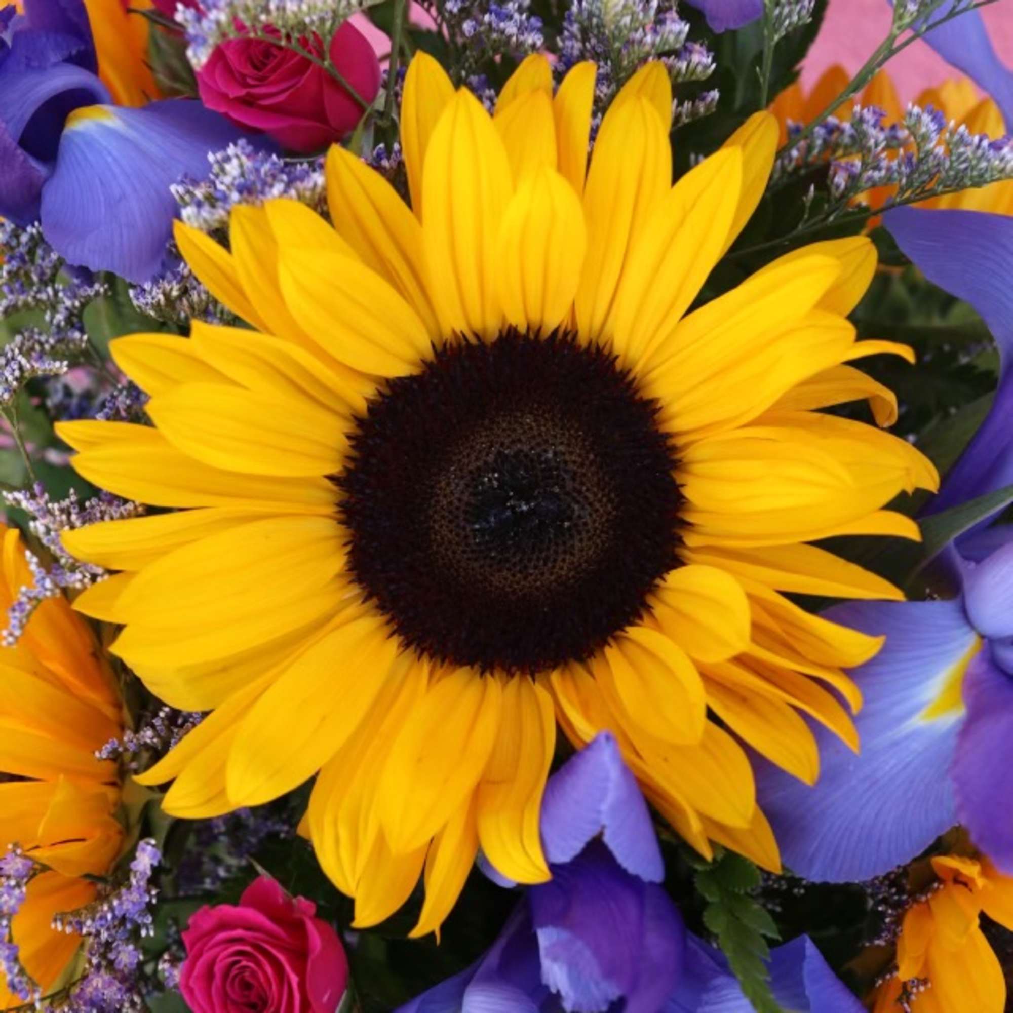 Bouquet with a large yellow sunflower, pink roses, and purple irises