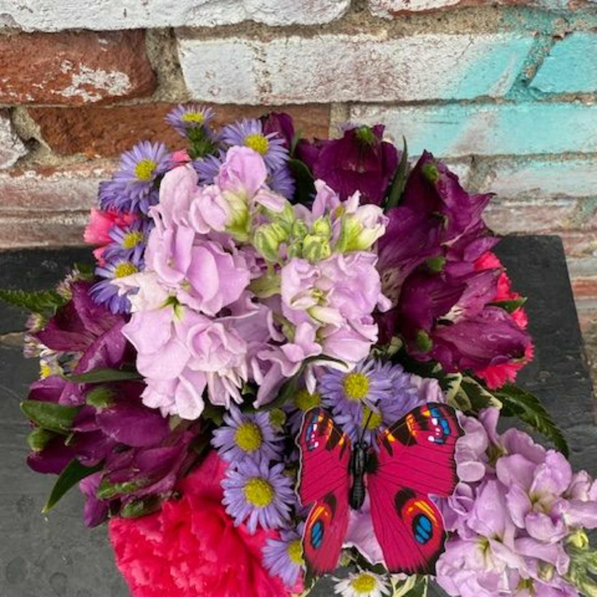 Bouquet of purple and pink flowers with a butterfly decoration