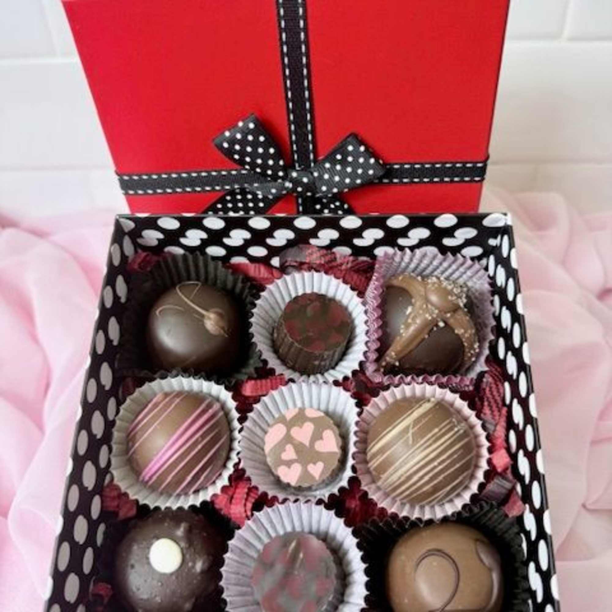 Box of assorted chocolates with a red lid and black ribbon