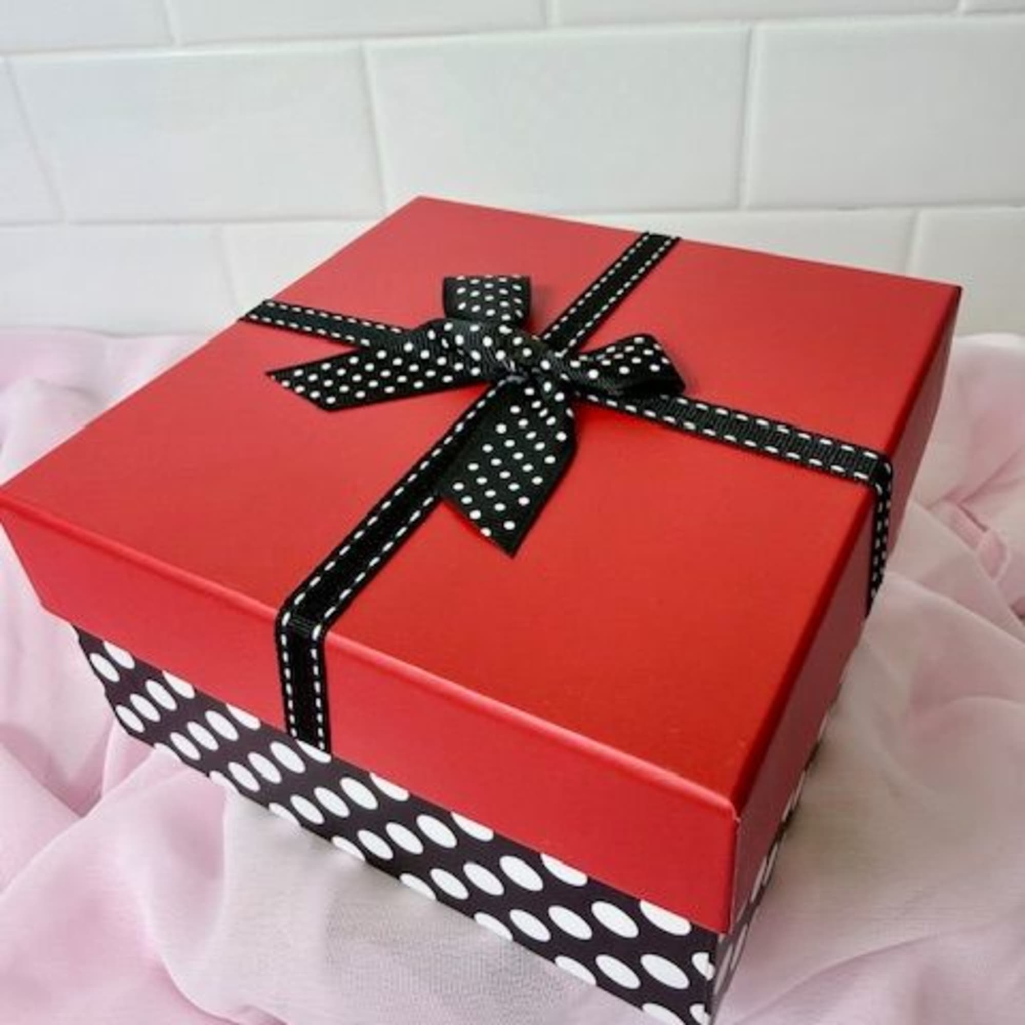 Red gift box with a black polka-dot ribbon and bow