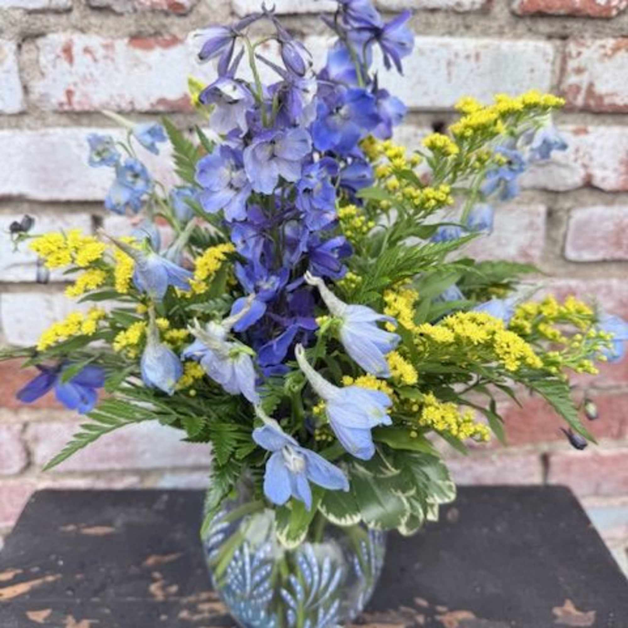 A tall spray of sky-blue delphinium-like blooms gives this everyday bouquet an