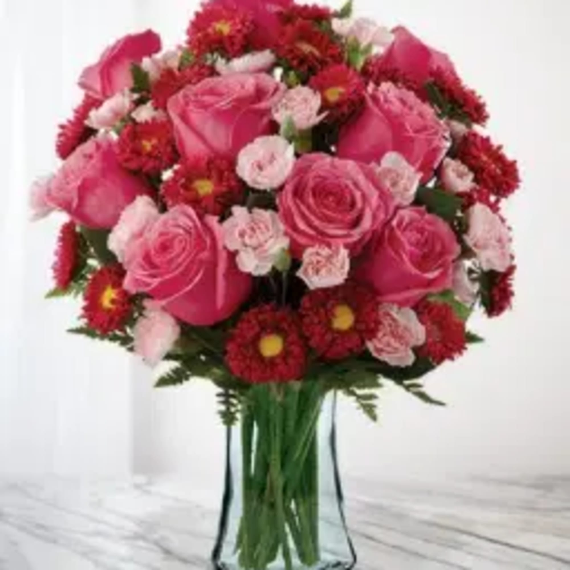Pink roses and red carnations arranged in a clear glass vase