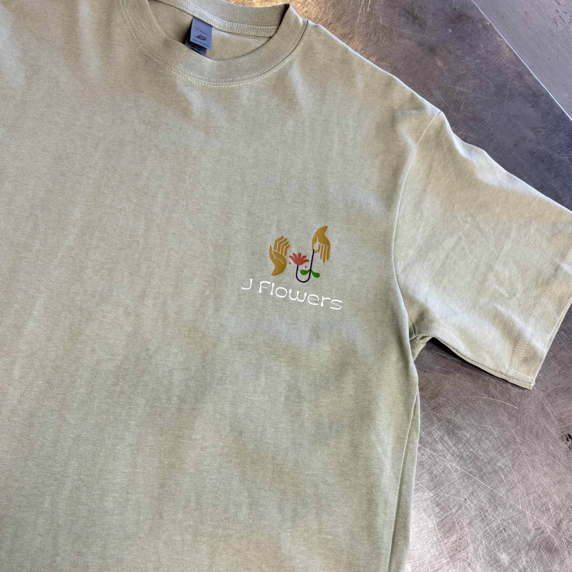 Light beige T-shirt with a small floral logo and text on the chest
