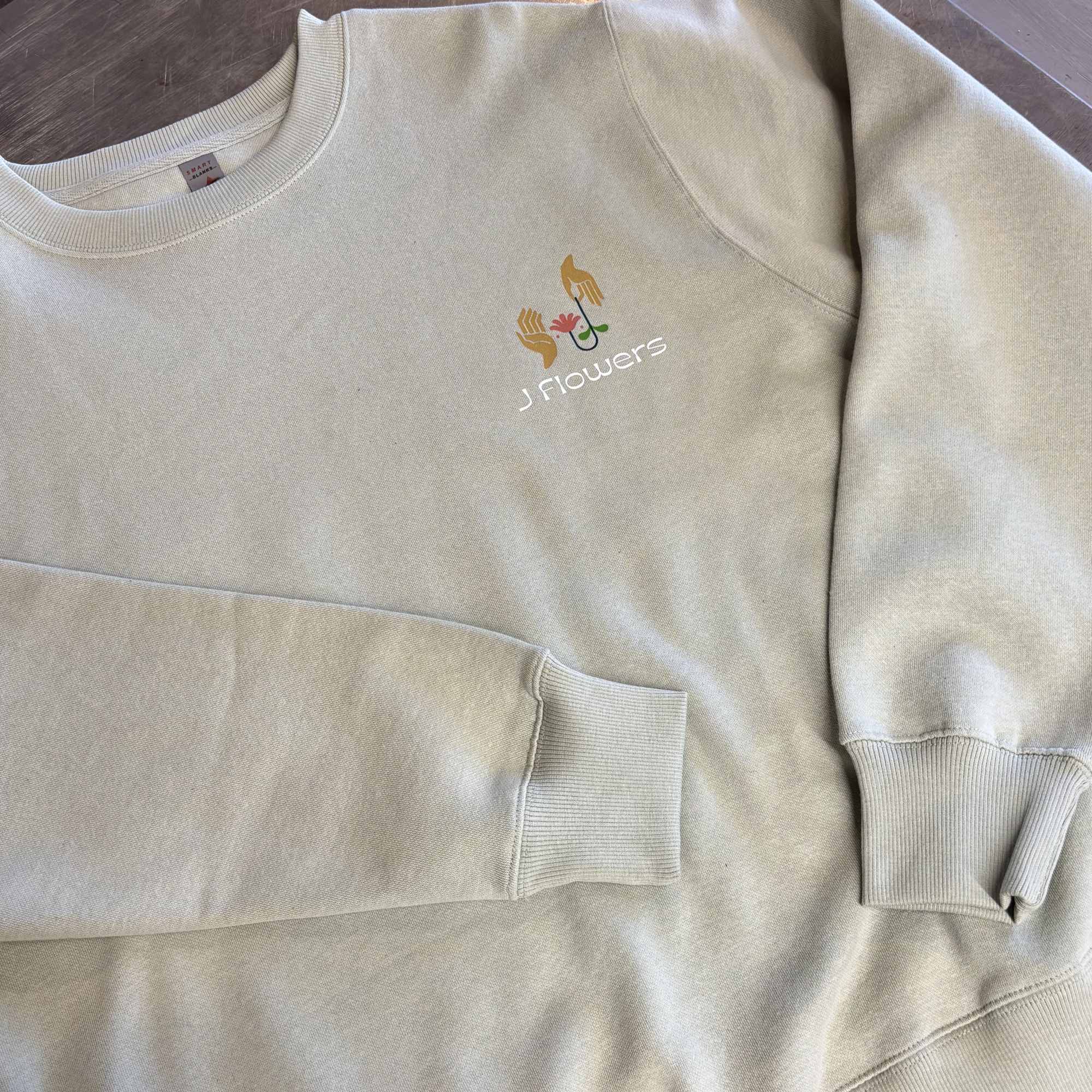 Beige sweatshirt with a small floral logo on the chest