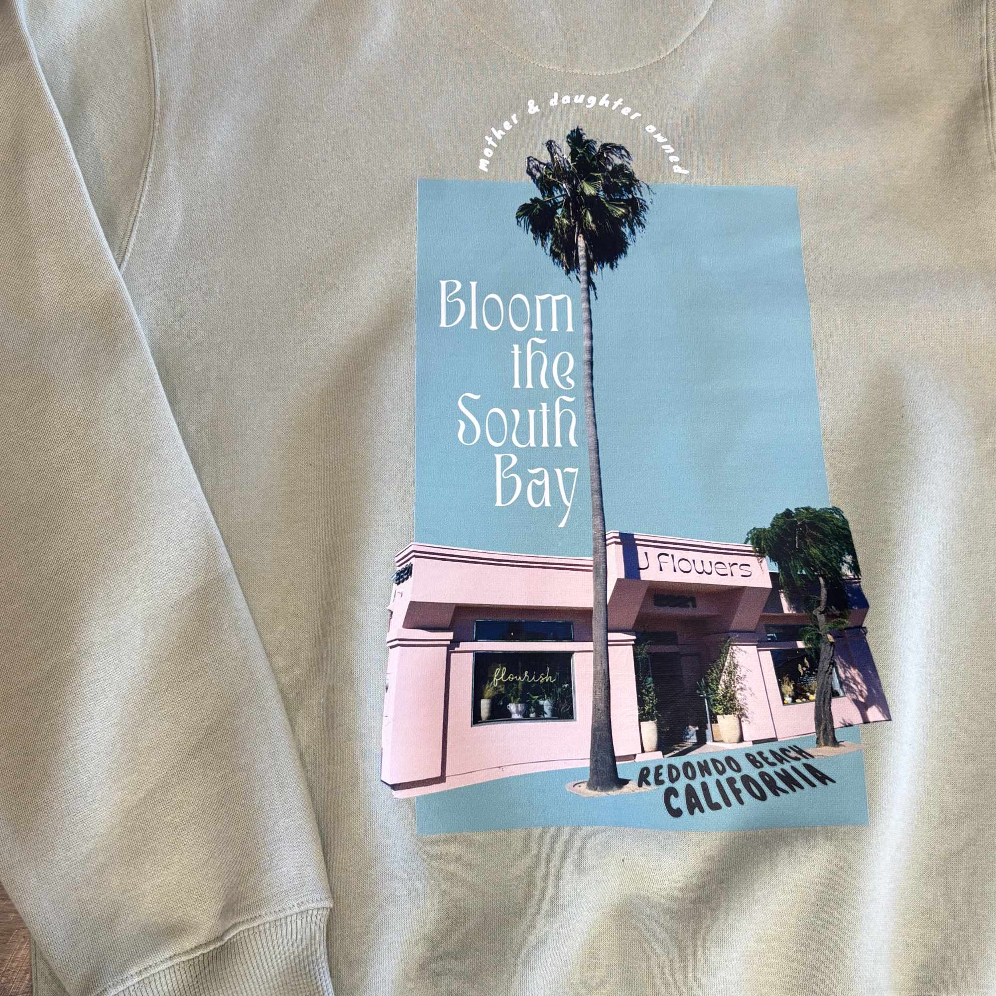 Beige sweatshirt with a printed flower shop graphic and palm trees