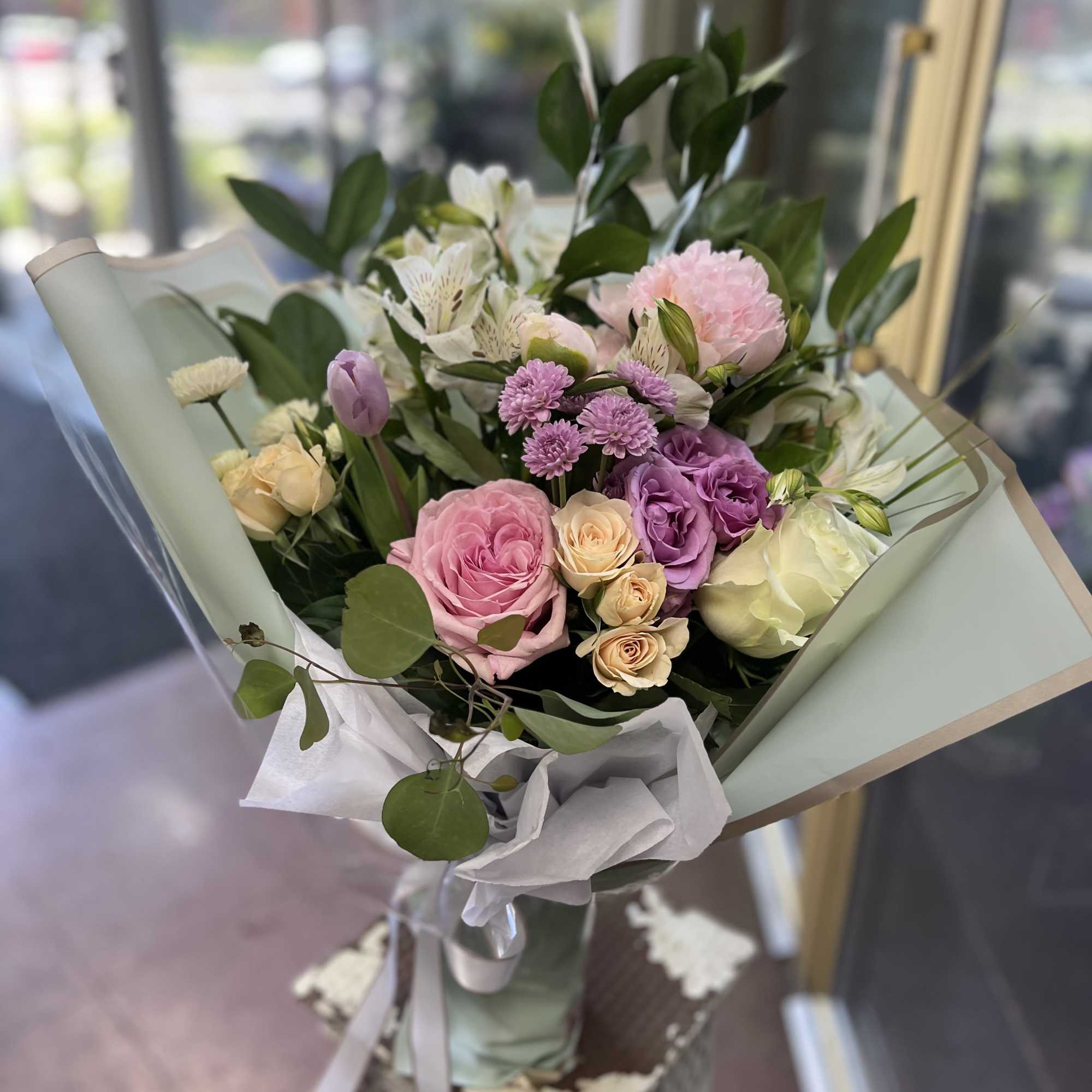 Bouquet of pink, purple, and white flowers wrapped in pale paper