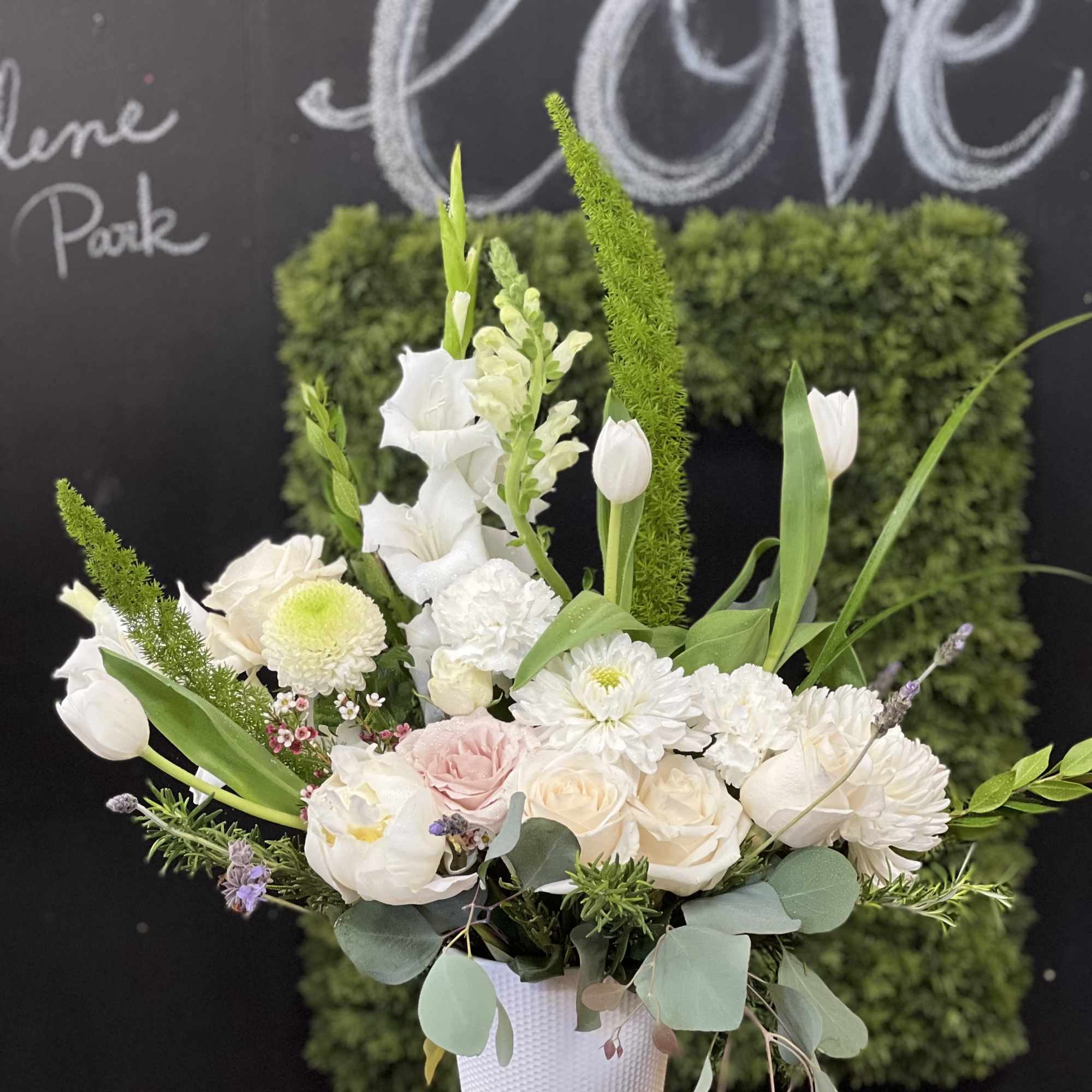 White floral arrangement in a textured white vase with pink accents
