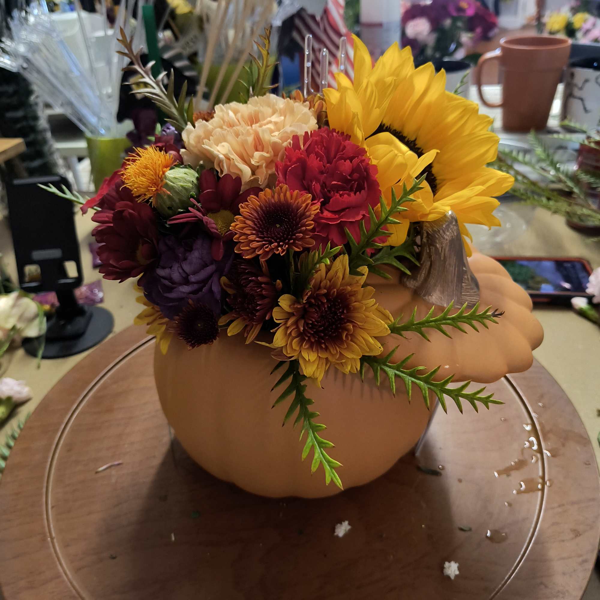 Fall floral arrangement in a pumpkin-shaped container with sunflowers and mums
