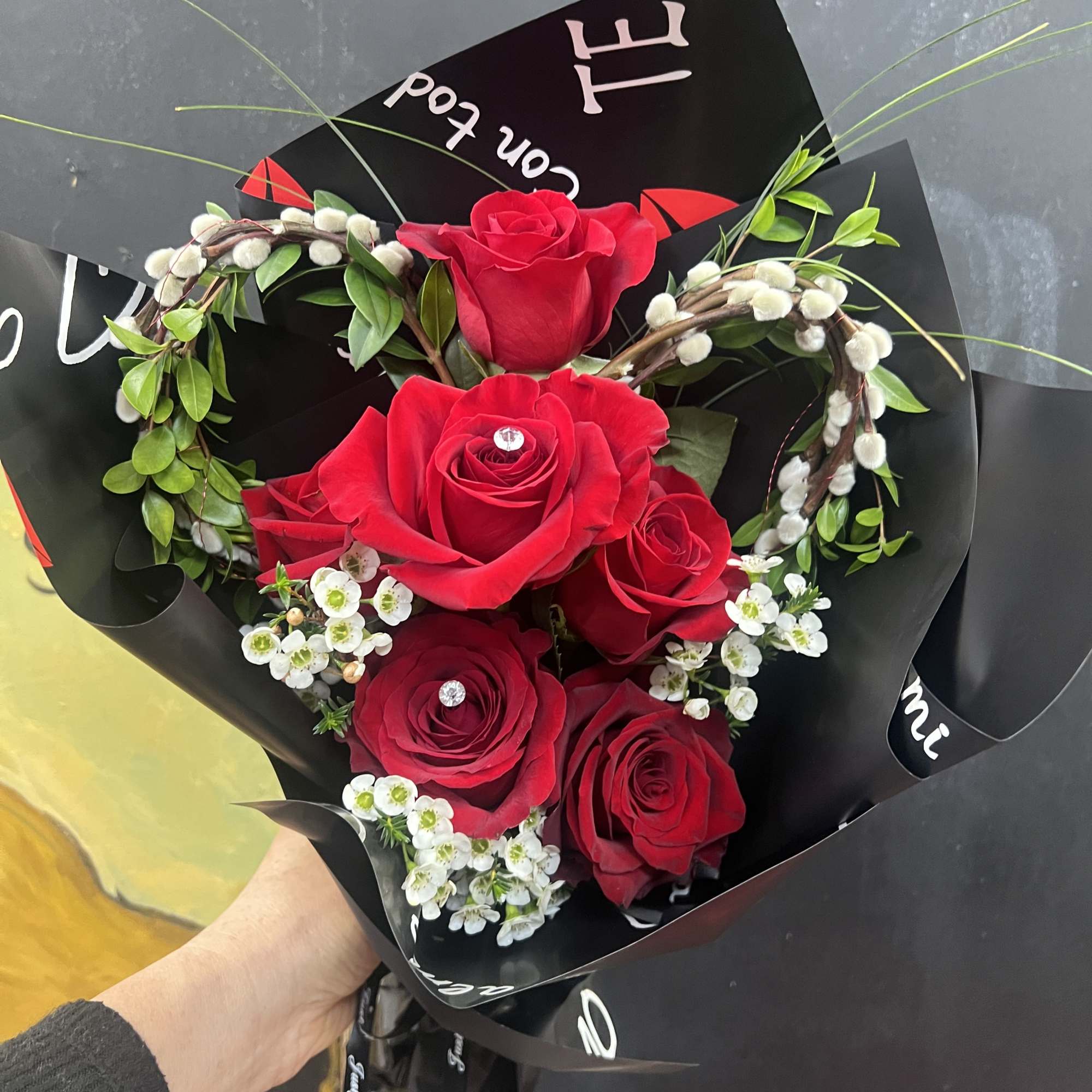 Bouquet of red roses with white filler flowers in black wrap