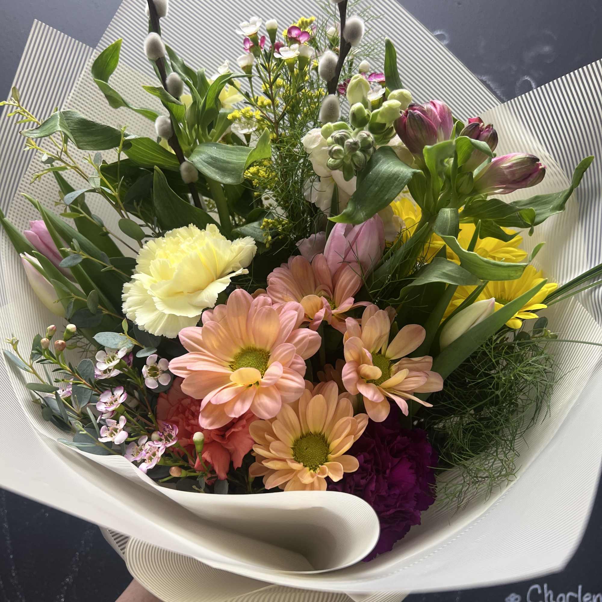 Mixed bouquet of pastel flowers wrapped in white paper