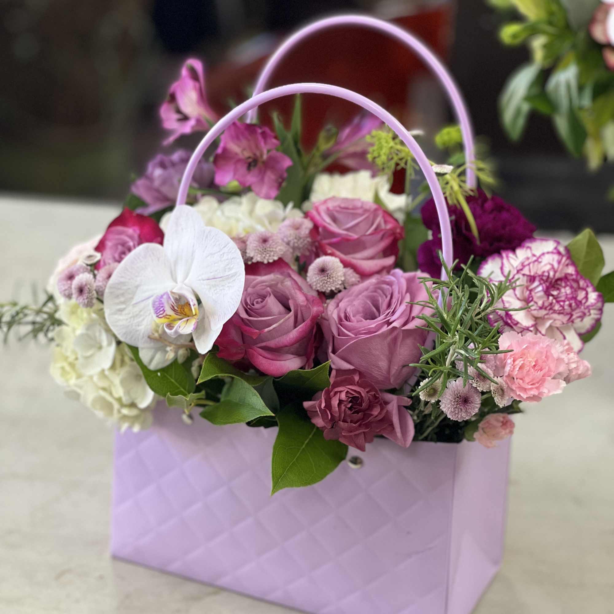 Pink and white flower arrangement in a lavender handled box