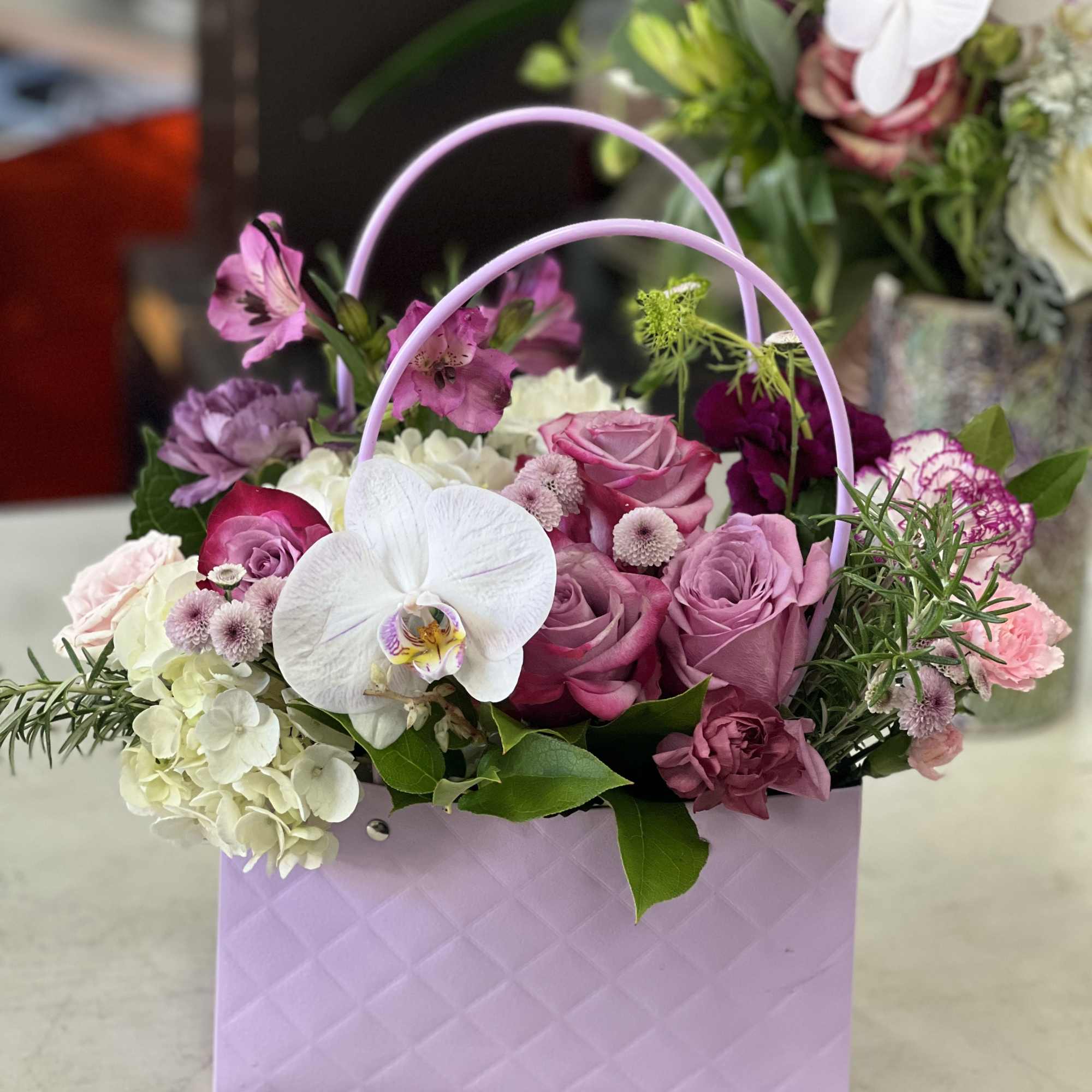 Pink and white flower arrangement in a lavender gift bag