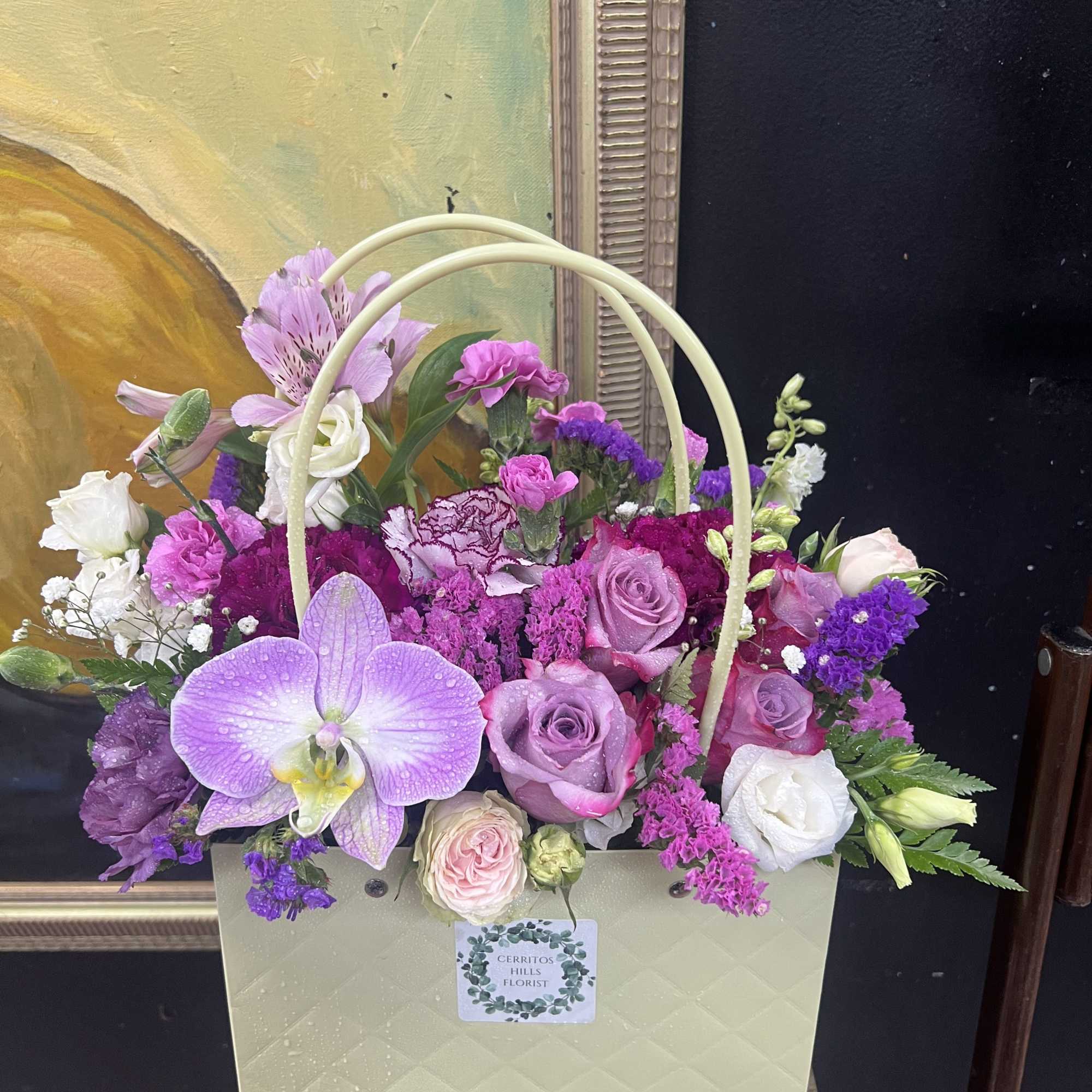 A soft lavender gift bag brimming with pink roses, white hydrangea, and