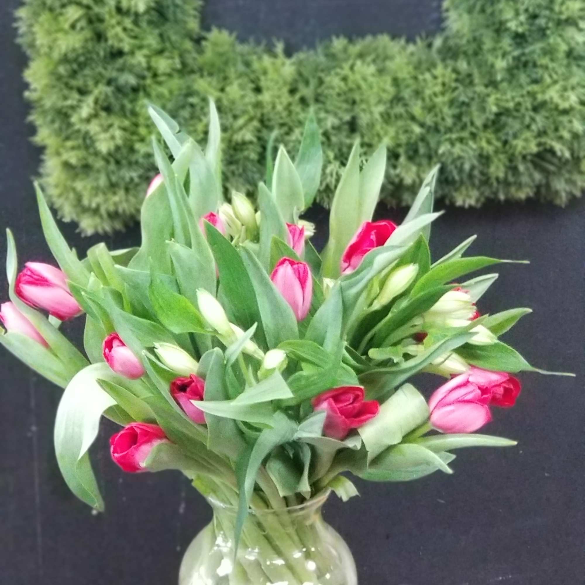Pink tulips in a clear glass vase on a small table