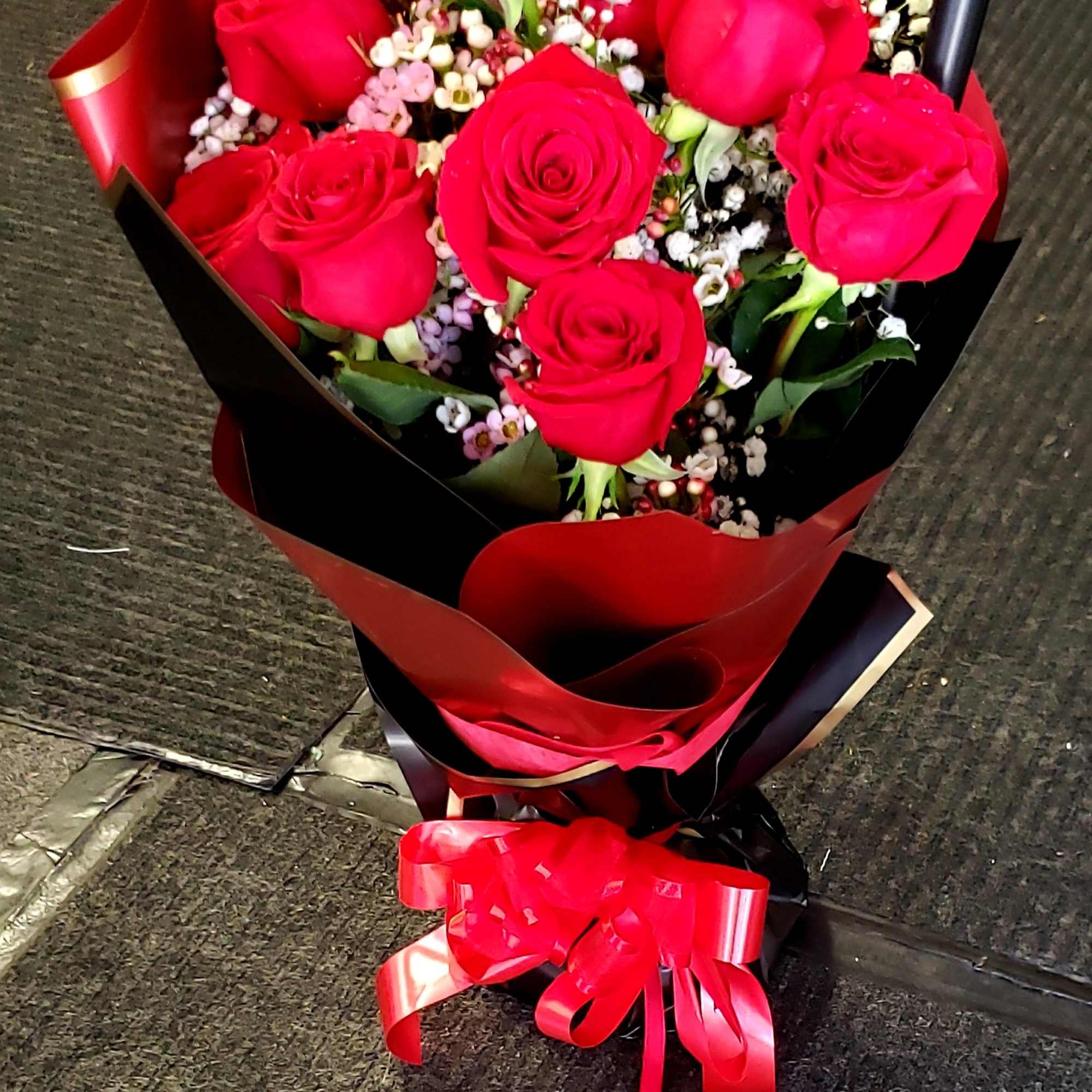 Bouquet of red roses with baby's breath wrapped in red and black paper