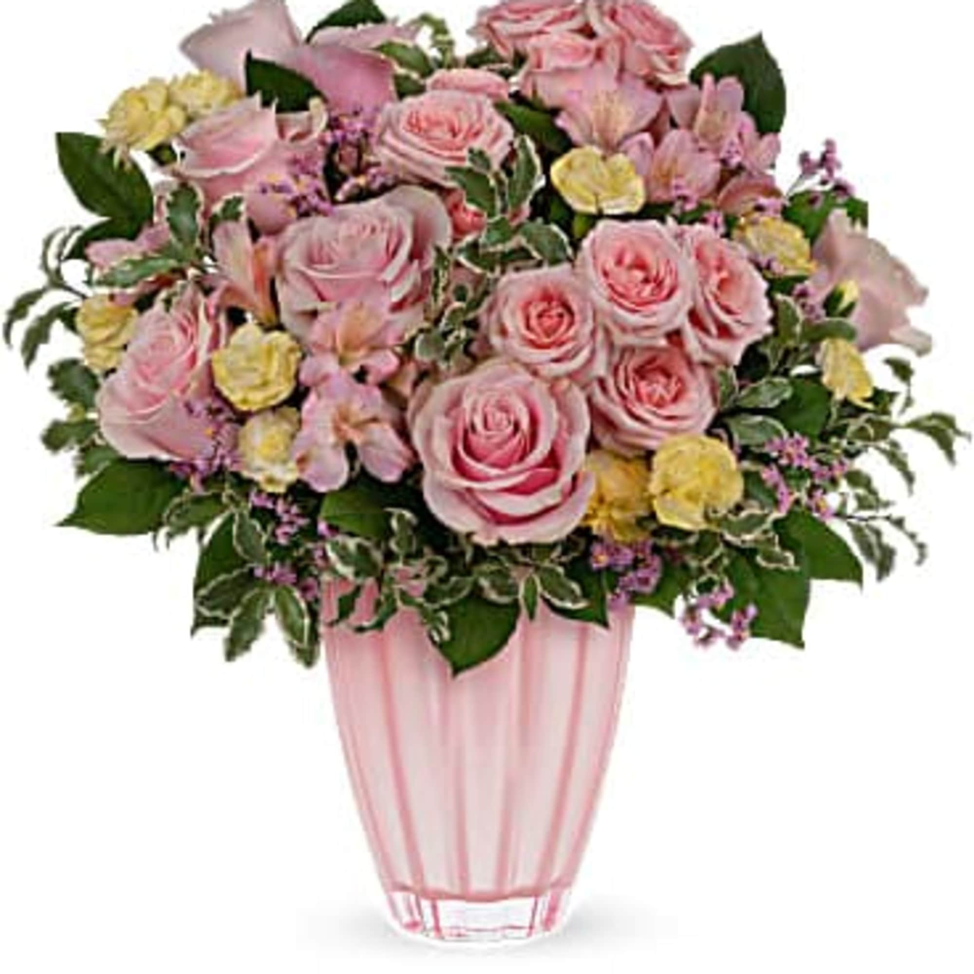 Pink roses and mixed blooms arranged in a pink glass vase