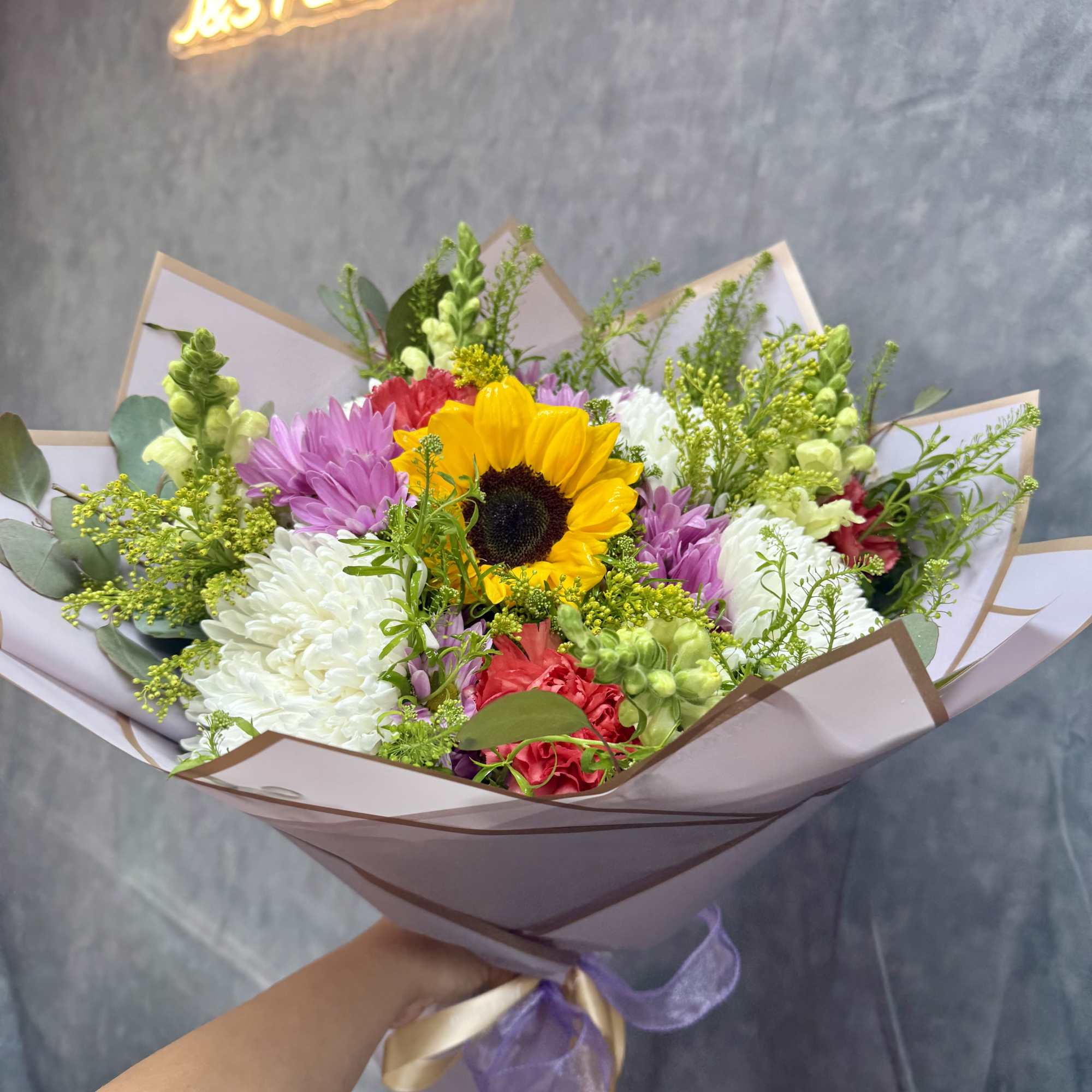 Bouquet with a sunflower, white and purple blooms, and pink flowers wrapped in paper